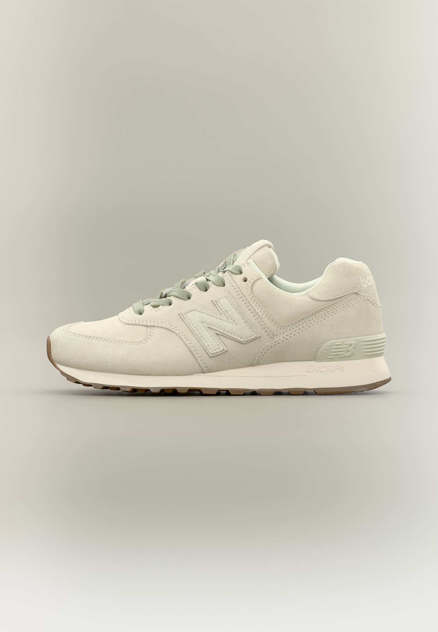Zapatilla New Balance beige claro con textura de ante, cordones y suela acolchada, mostrada de lado sobre un fondo neutro.