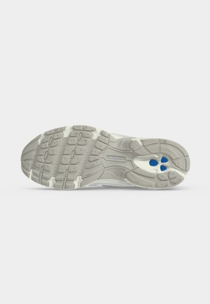 Suela de zapato con patrón de banda de rodadura en gris y blanco, elementos de amortiguación azules y logotipo "new balance" en el centro.