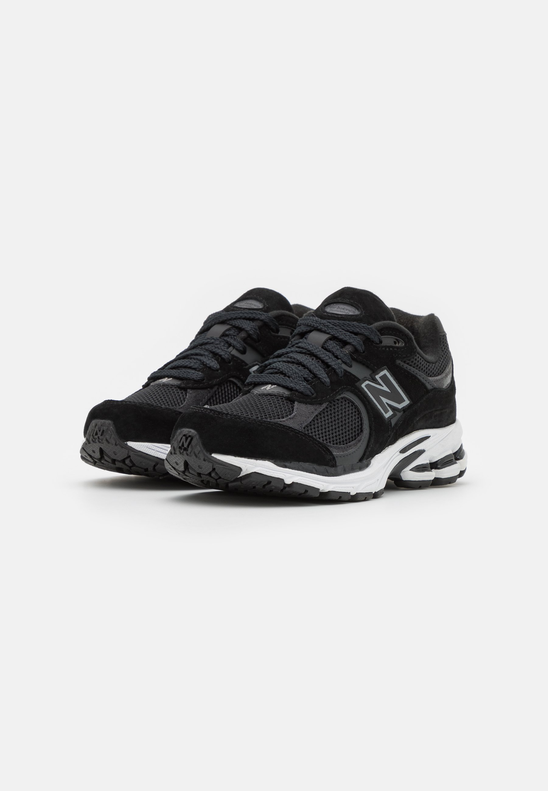 Zapatillas deportivas negras con parte superior de malla y ante, cierre de cordones, detalle de logo y suela de goma texturizada con acentos de amortiguación.