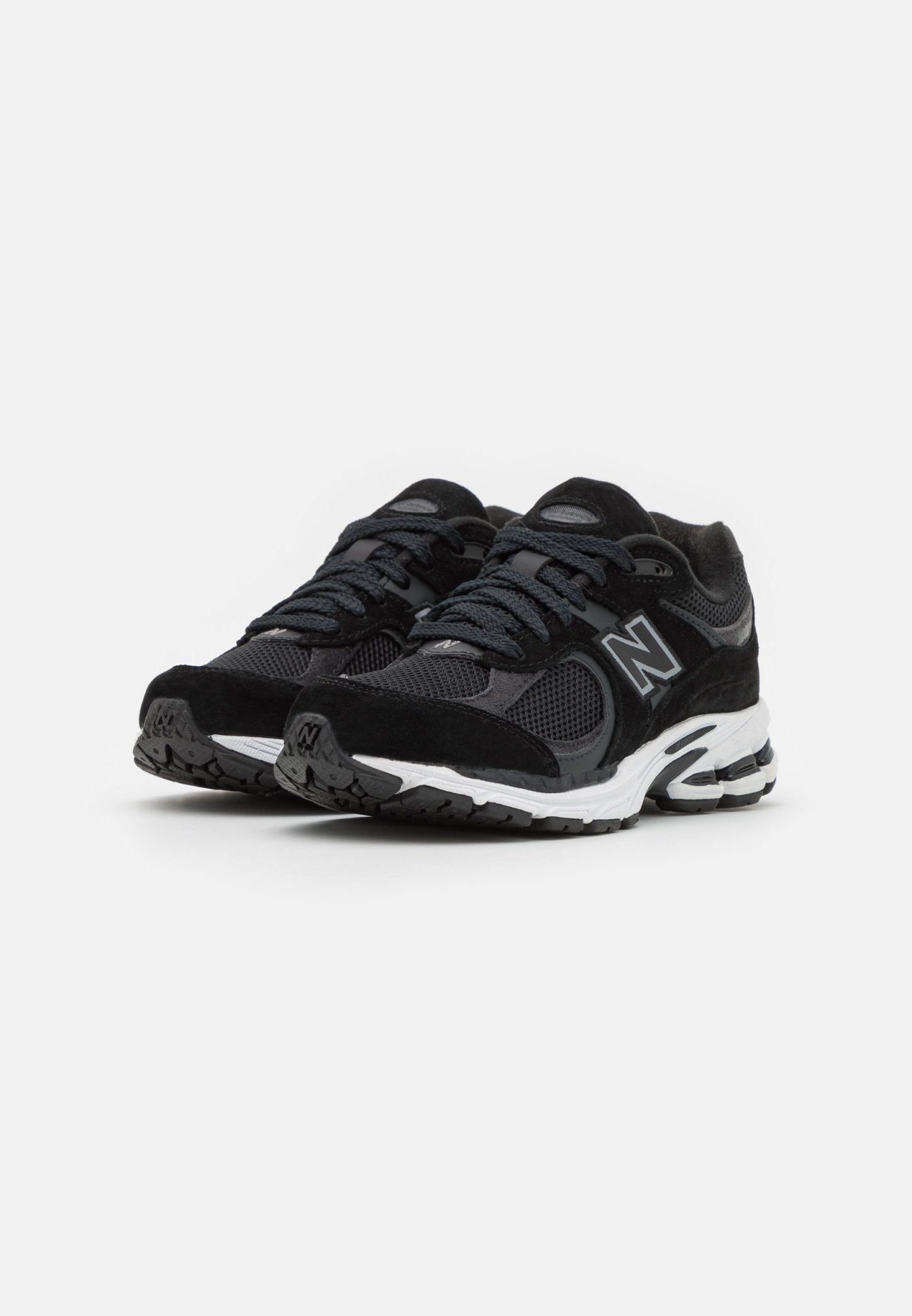 Zapatillas deportivas negras con parte superior de malla y ante, cierre de cordones, detalle de logo y suela de goma texturizada con acentos de amortiguación.