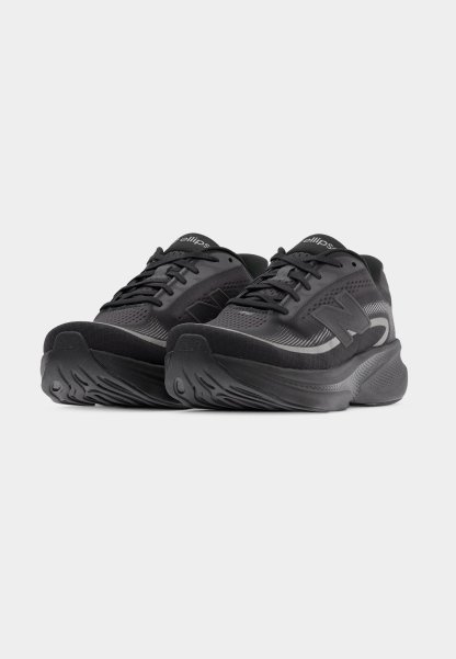 Zapatillas deportivas negras con parte superior de malla, cuello acolchado y patrones texturizados en la suela. Cordones y detalles de la marca en un gris contrastante.