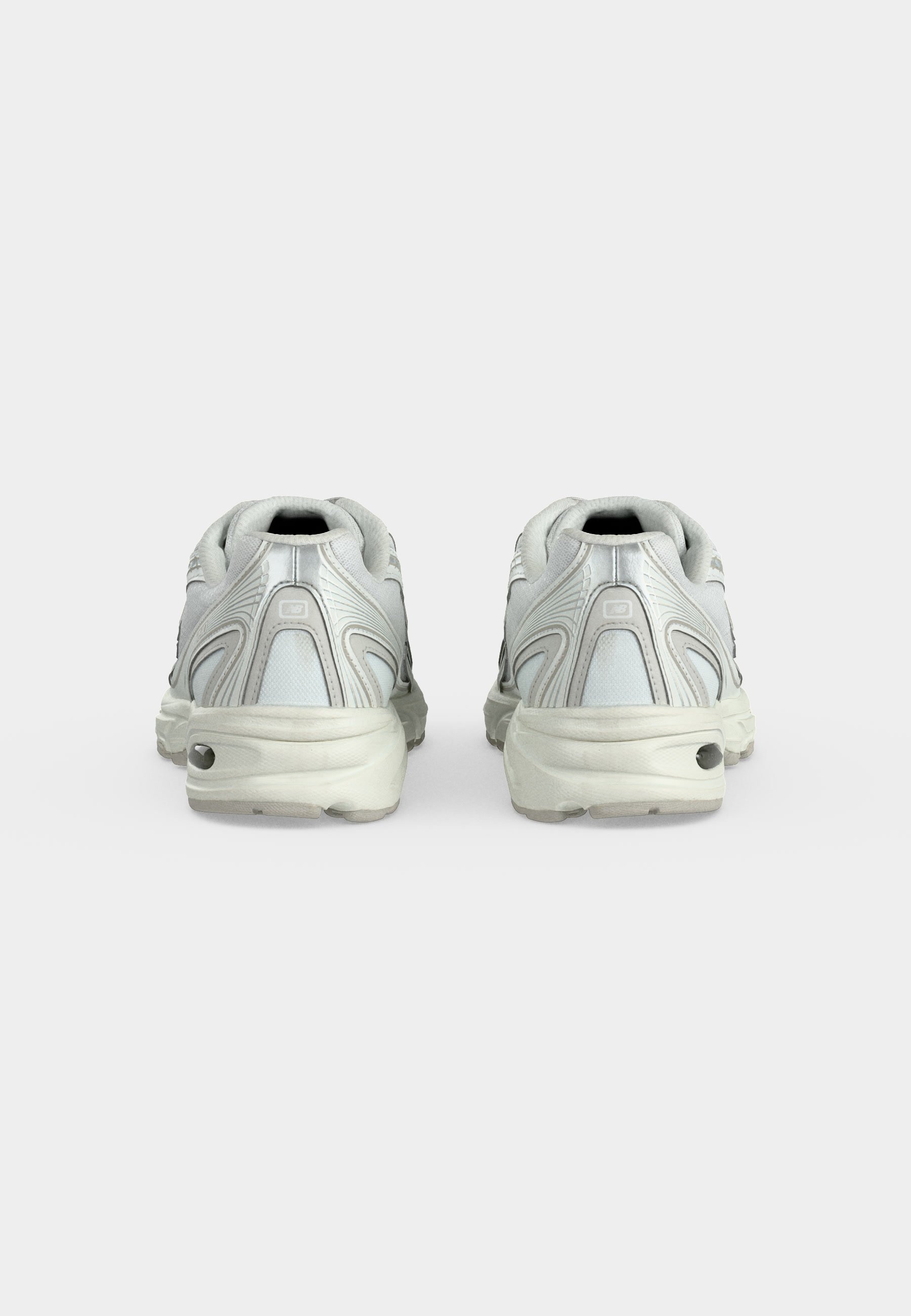 Par de zapatillas deportivas blancas con suelas gruesas mostradas desde atrás sobre un fondo blanco liso.
