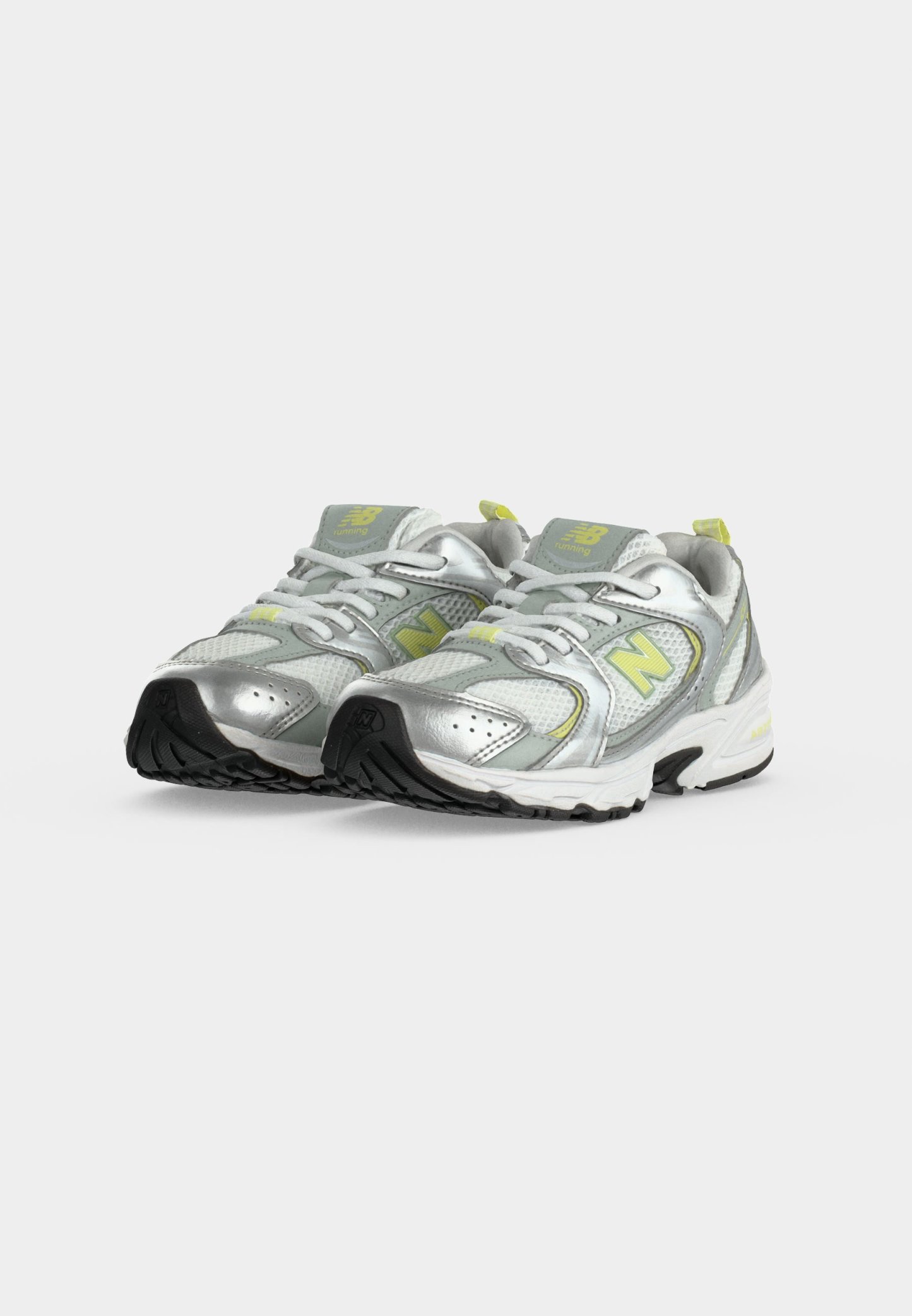 Par de zapatillas de correr plateadas y grises con detalles amarillos y suelas negras, colocadas lado a lado sobre un fondo blanco.