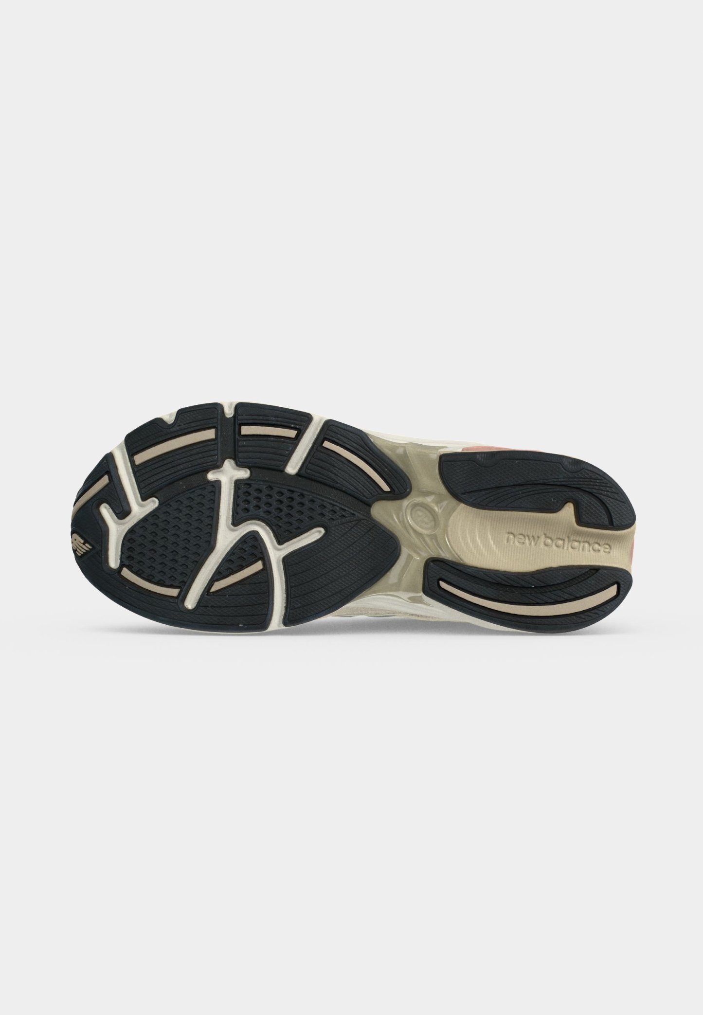 Suela de zapato New Balance con banda de rodadura negra y entresuela beige, mostrando patrones de agarre texturizados y texto "new balance" en la zona del talón.