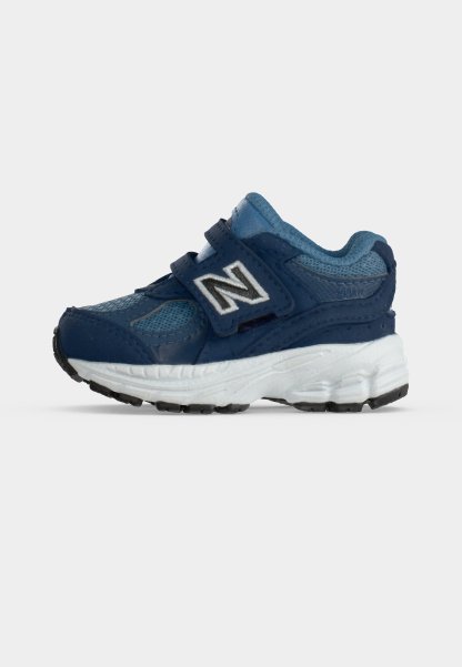 Zapatilla azul y azul marino para niños pequeños con suela blanca y tiras de velcro que presentan un logo blanco "N" en el lateral.