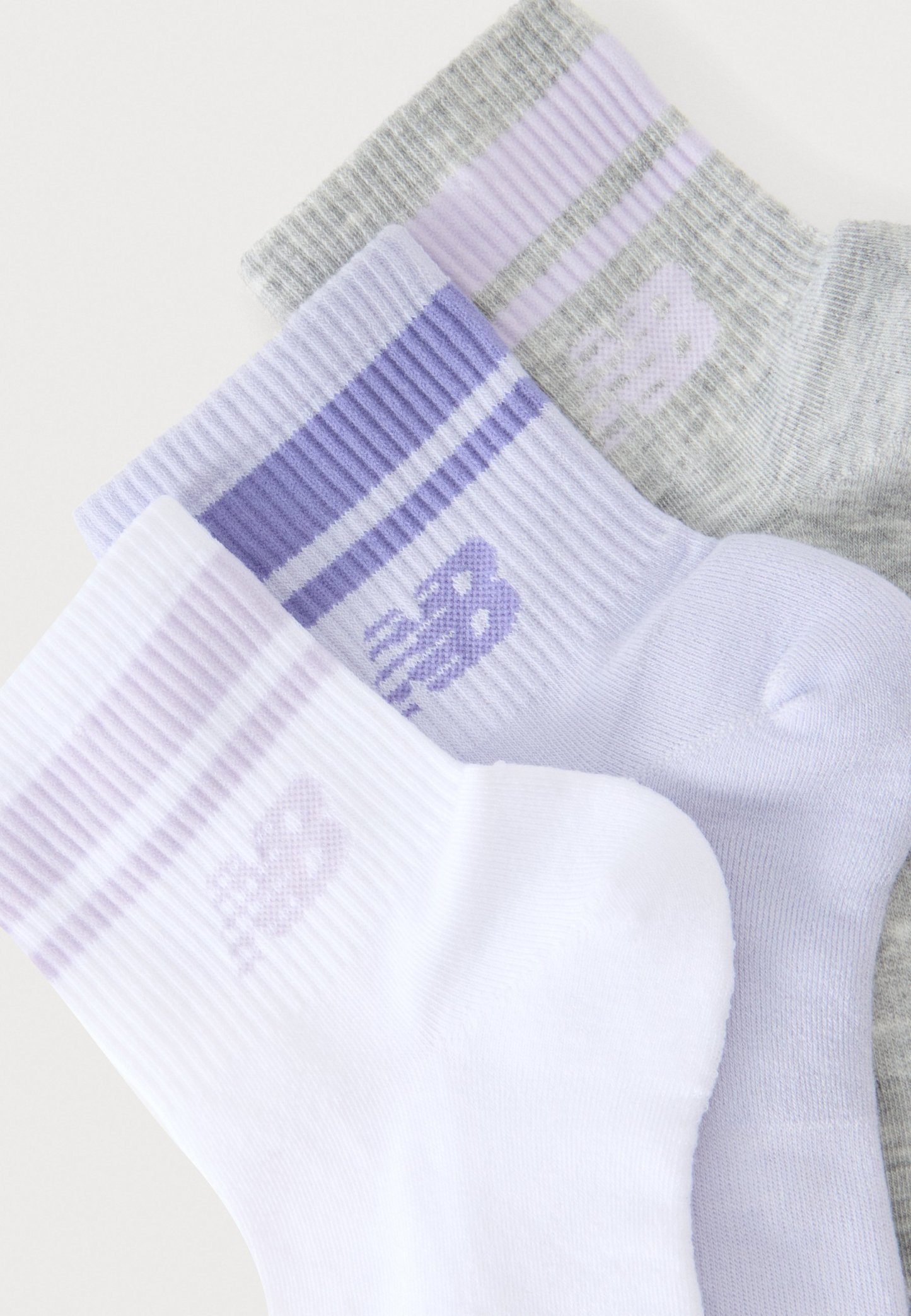 Tres pares de calcetines de caña media con canalé en blanco, lila claro y gris, cada uno con un pequeño gráfico estilizado de un animal cerca del puño.