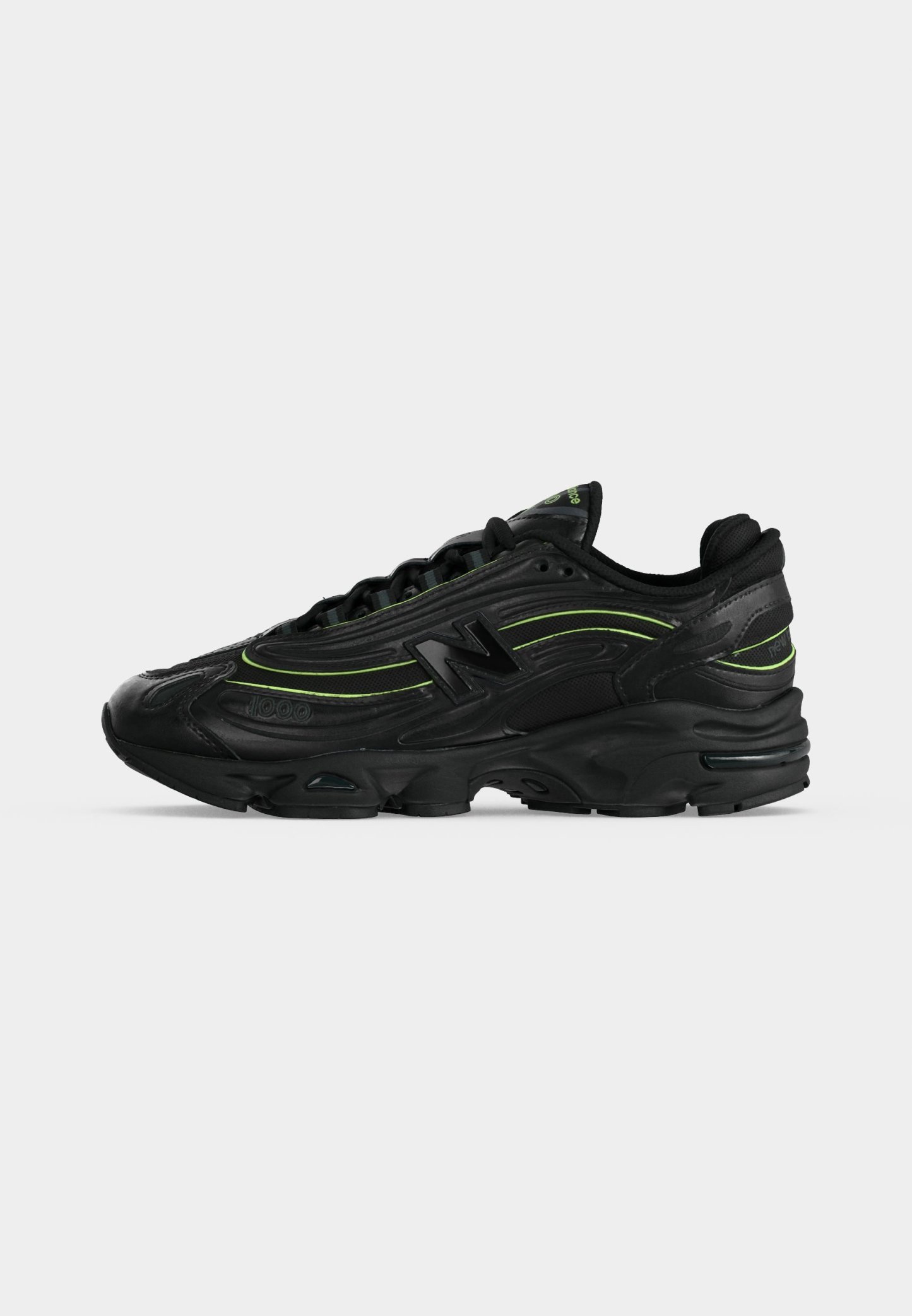 Zapatilla deportiva negra con detalles en verde neón, suela gruesa y logo "N" en el lateral, vista desde el lado exterior.