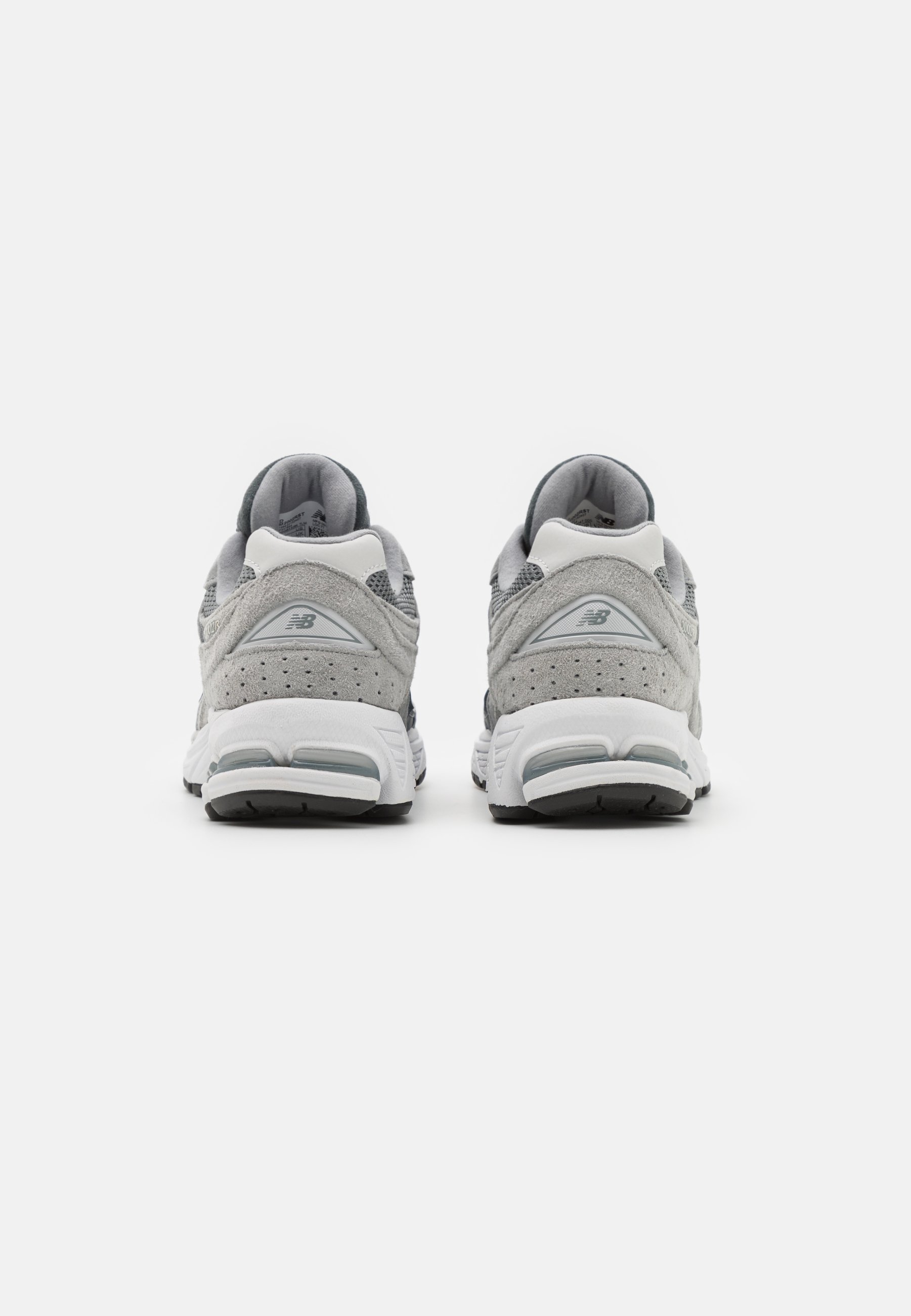 Zapatillas deportivas grises con parte superior de ante y malla, que cuentan con una entresuela blanca, cuellos acolchados y suelas exteriores de goma negra.