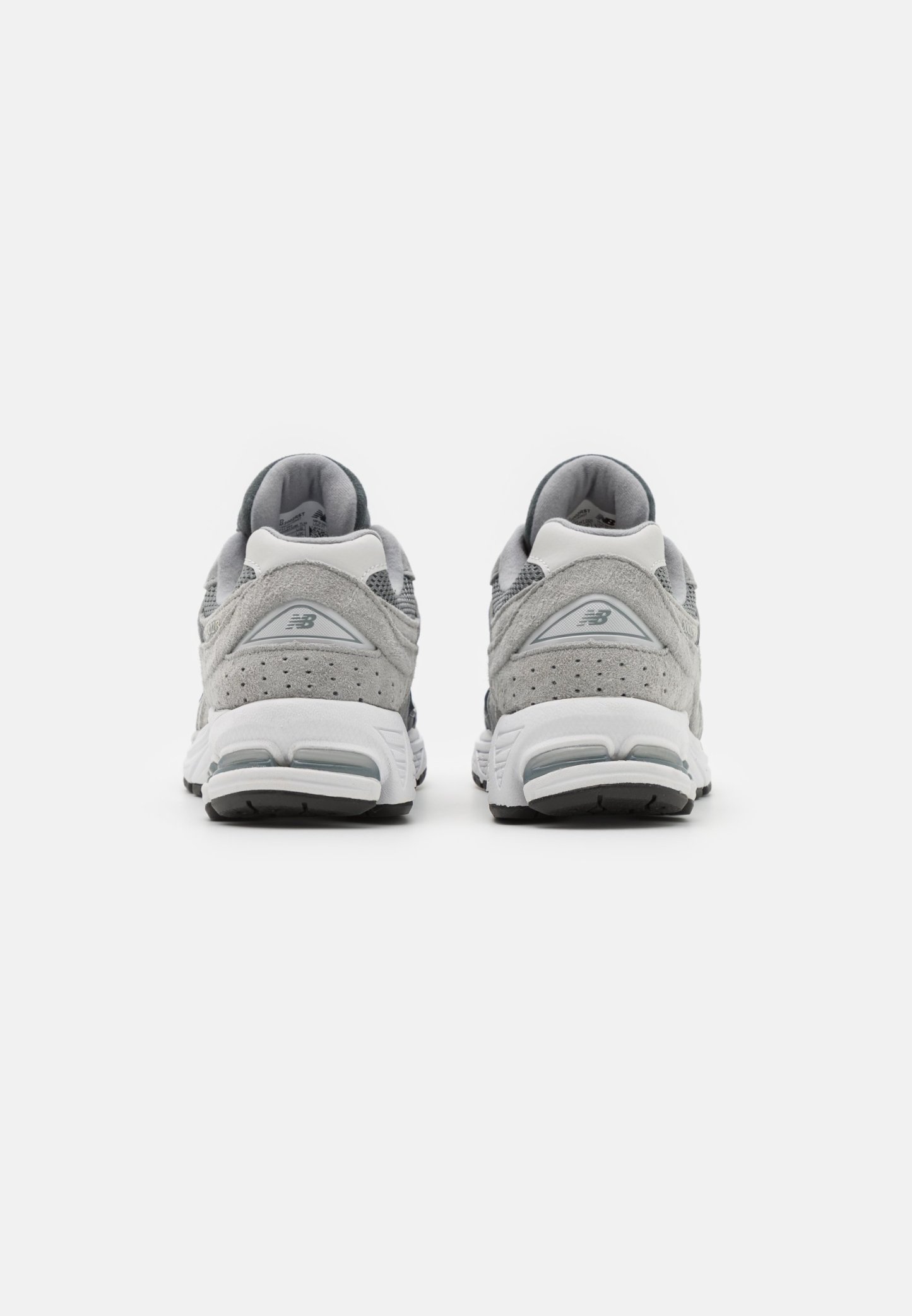 Zapatillas deportivas grises con parte superior de ante y malla, que cuentan con una entresuela blanca, cuellos acolchados y suelas exteriores de goma negra.