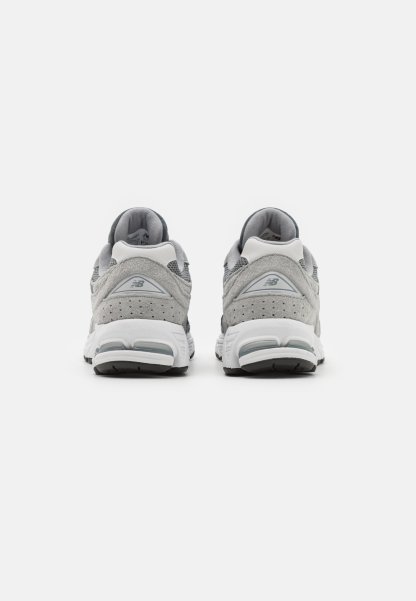Zapatillas deportivas grises con parte superior de ante y malla, que cuentan con una entresuela blanca, cuellos acolchados y suelas exteriores de goma negra.
