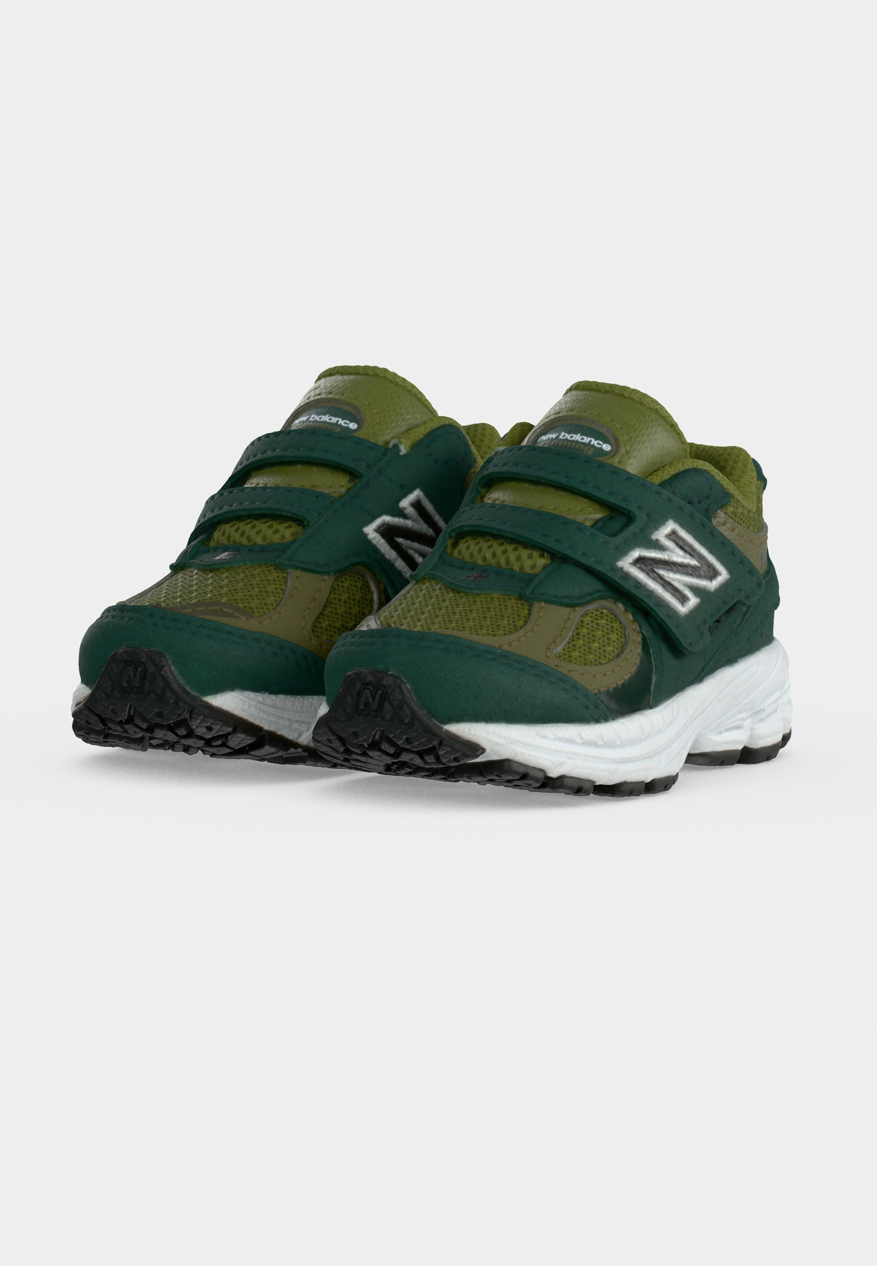 Zapatillas para niños pequeños New Balance en verde y verde oscuro con medias suelas blancas y suelas exteriores negras, con tiras de velcro y paneles de tela de malla.