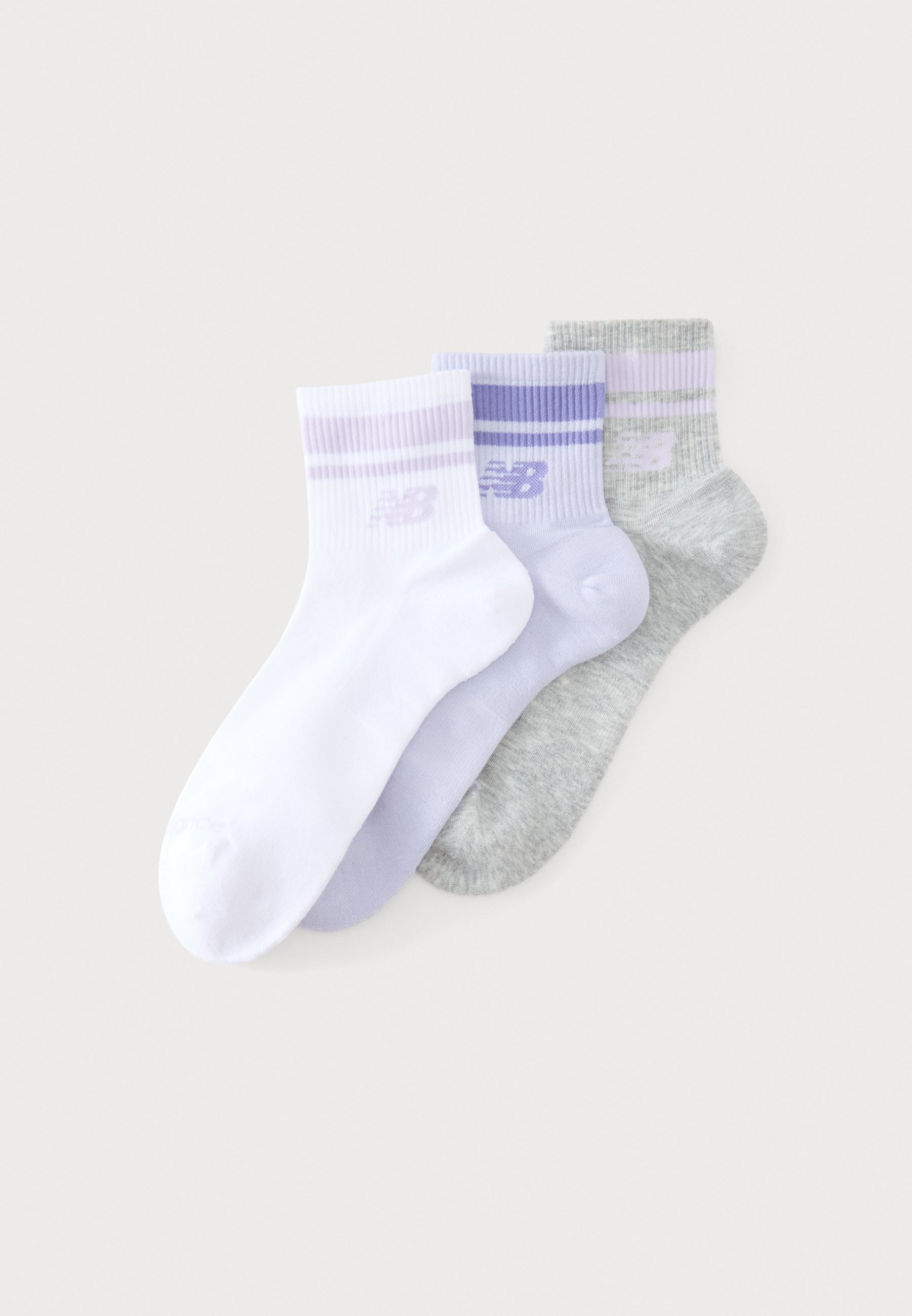 Tres calcetines tobilleros en blanco, lila claro y gris con rayas a juego y un logo de New Balance en los puños.