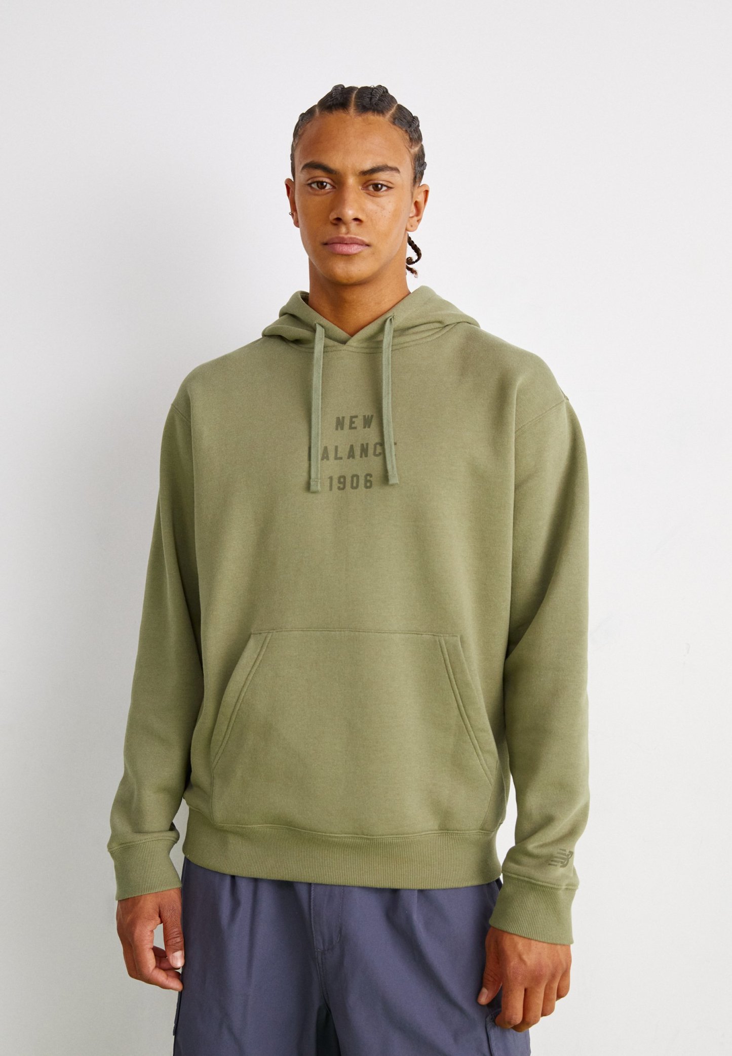 Sudadera de algodón verde con un bolsillo canguro en la parte frontal, capucha con cordón y un sutil estampado de logo en un tono más oscuro. Textura suave y corte relajado.