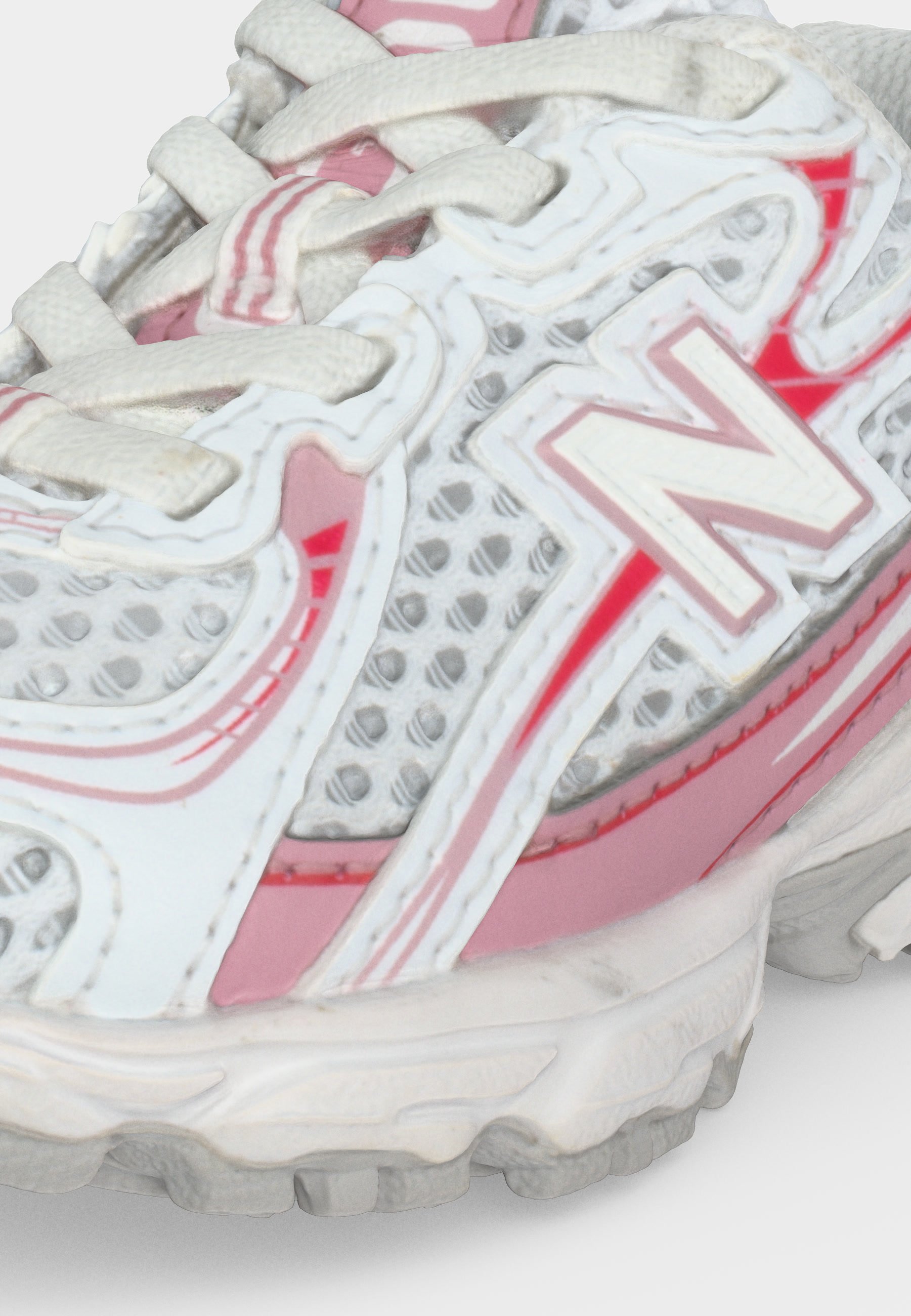 Zapatilla de running New Balance blanca y rosa con tejido de malla, cordones blancos y suela texturizada, mostrada en detalle en primer plano.