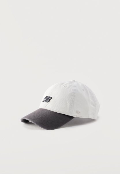 Gorra de béisbol blanca y gris oscuro con el logo de New Balance bordado en la parte frontal y la marca '47 cosida en el lateral.
