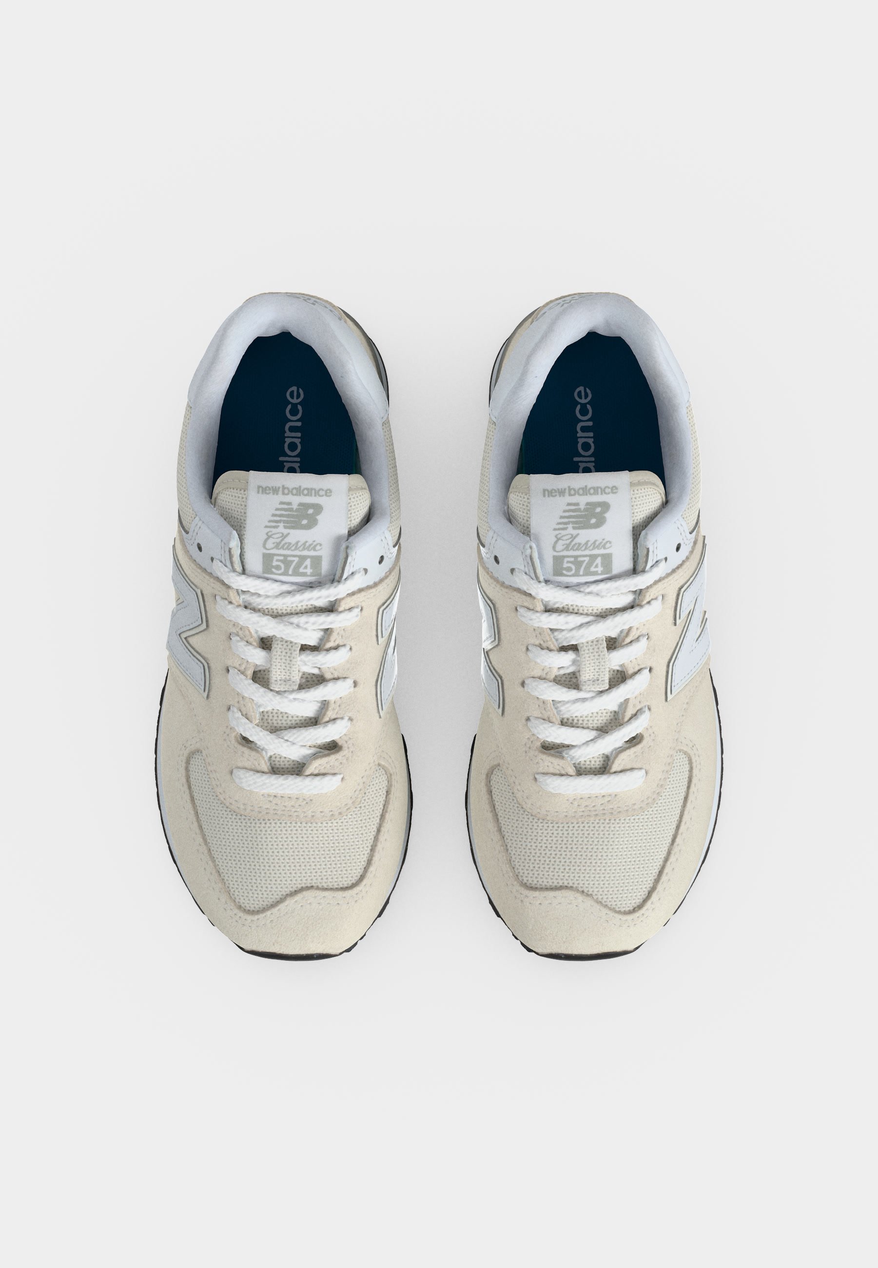 Par de zapatillas New Balance 574 Classic beige y blancas vistas desde arriba sobre un fondo claro.