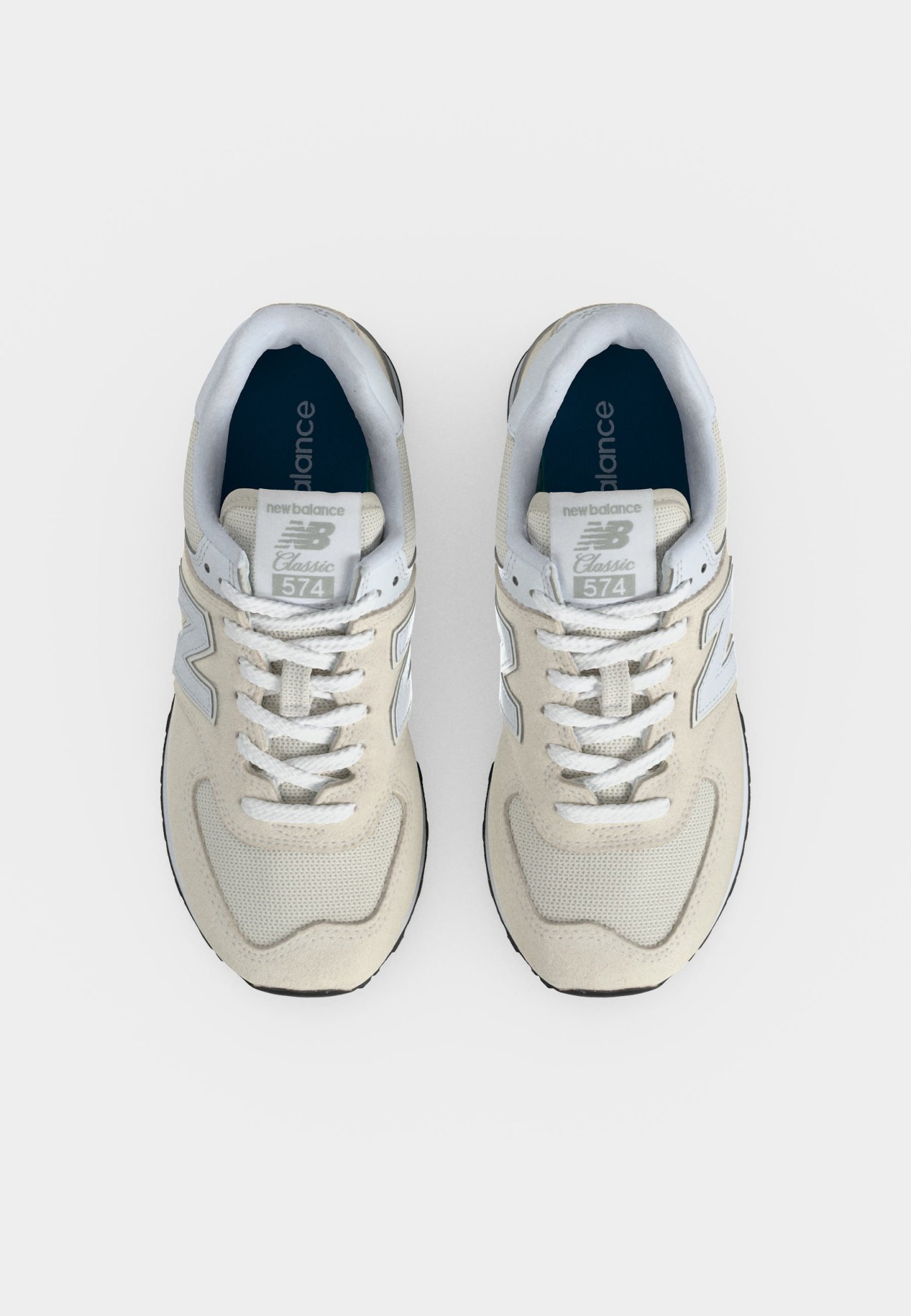 Par de zapatillas New Balance 574 Classic beige y blancas vistas desde arriba sobre un fondo claro.