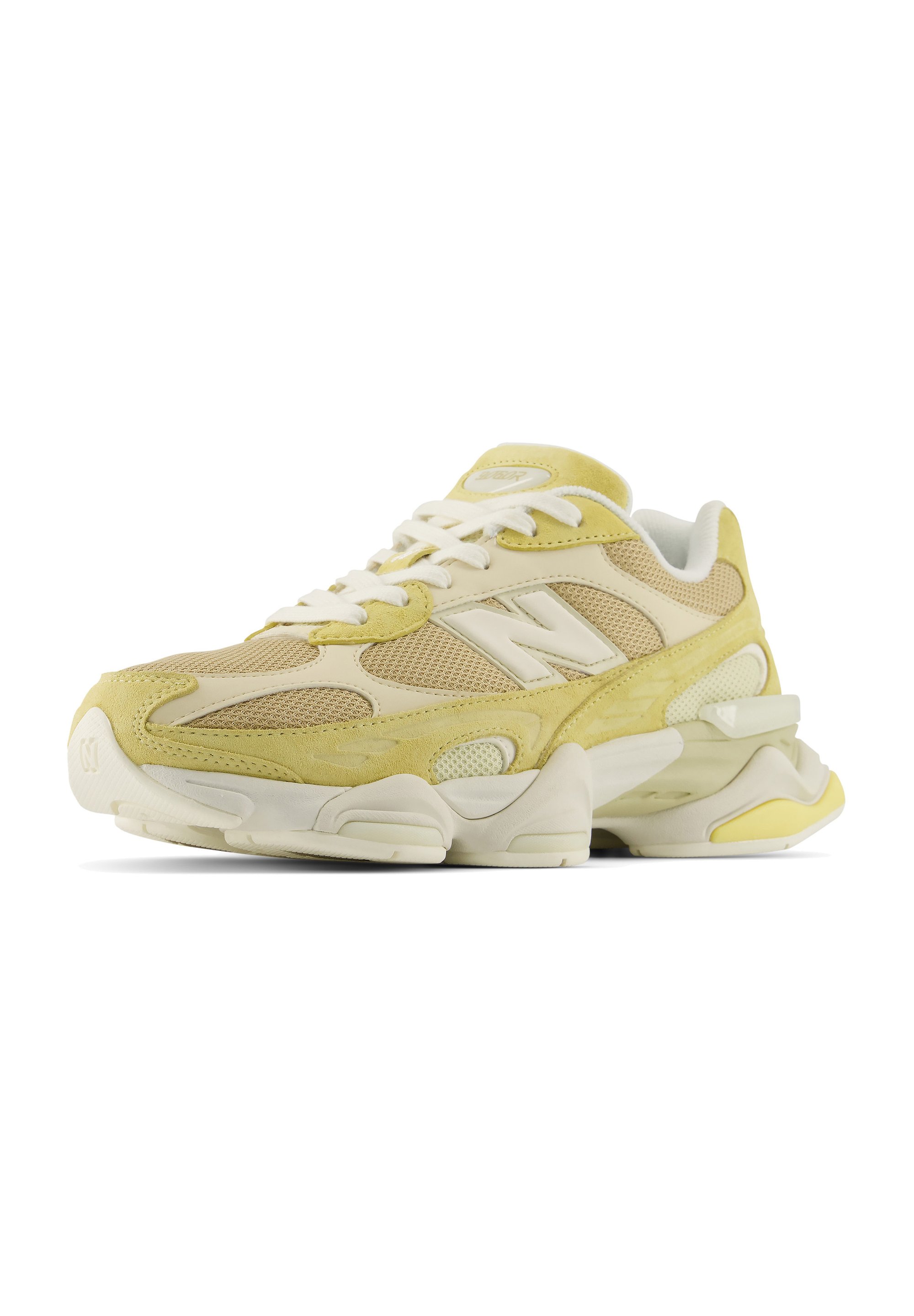 Zapatilla New Balance crema y amarilla con paneles de malla, cordones blancos y suela gruesa mostrada desde el frente sobre fondo blanco.