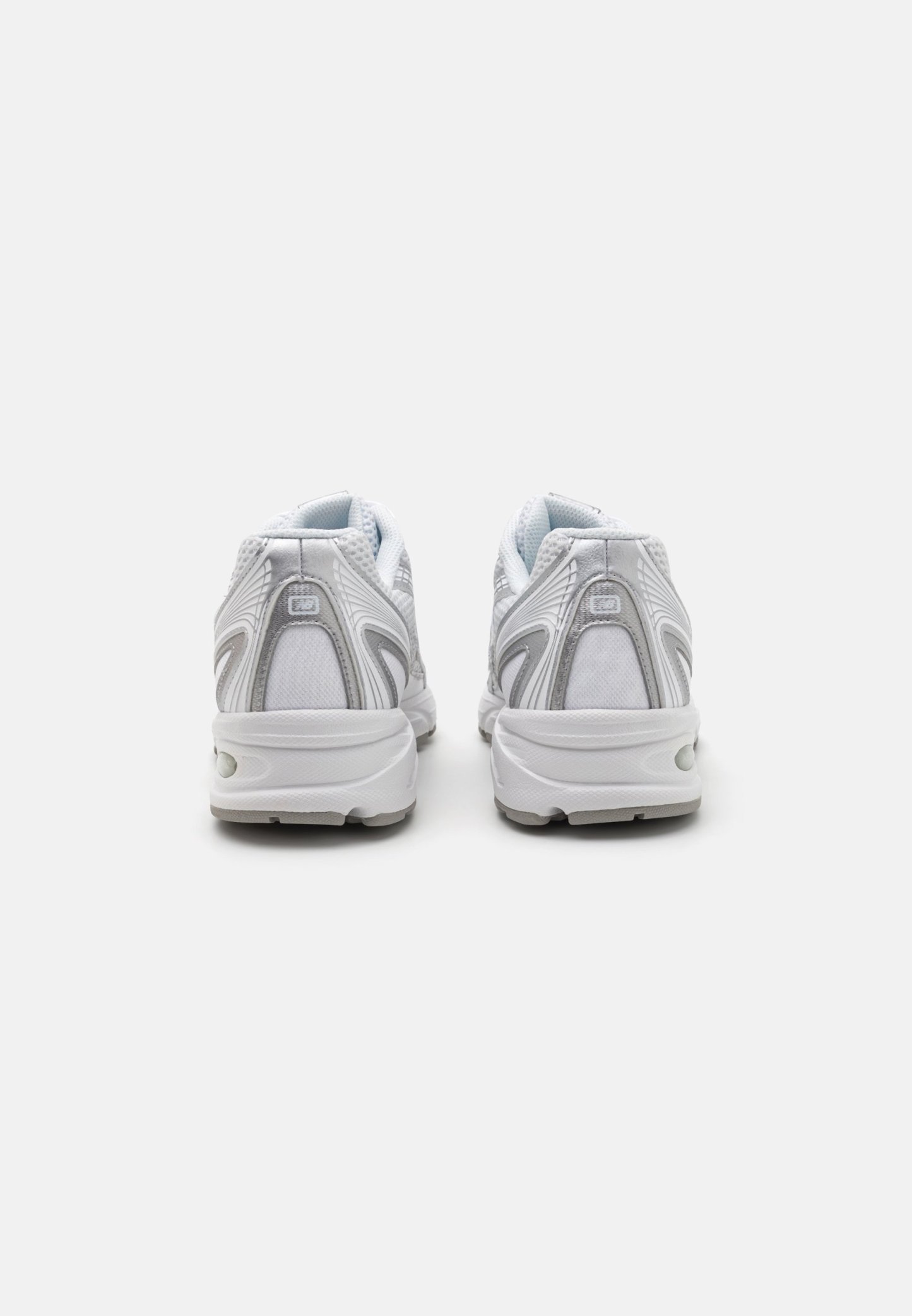 Zapatillas deportivas blancas con parte superior de malla, acentos plateados, cuello acolchado y suela en contraste. Presenta una puntera redondeada y detalles de ventilación.