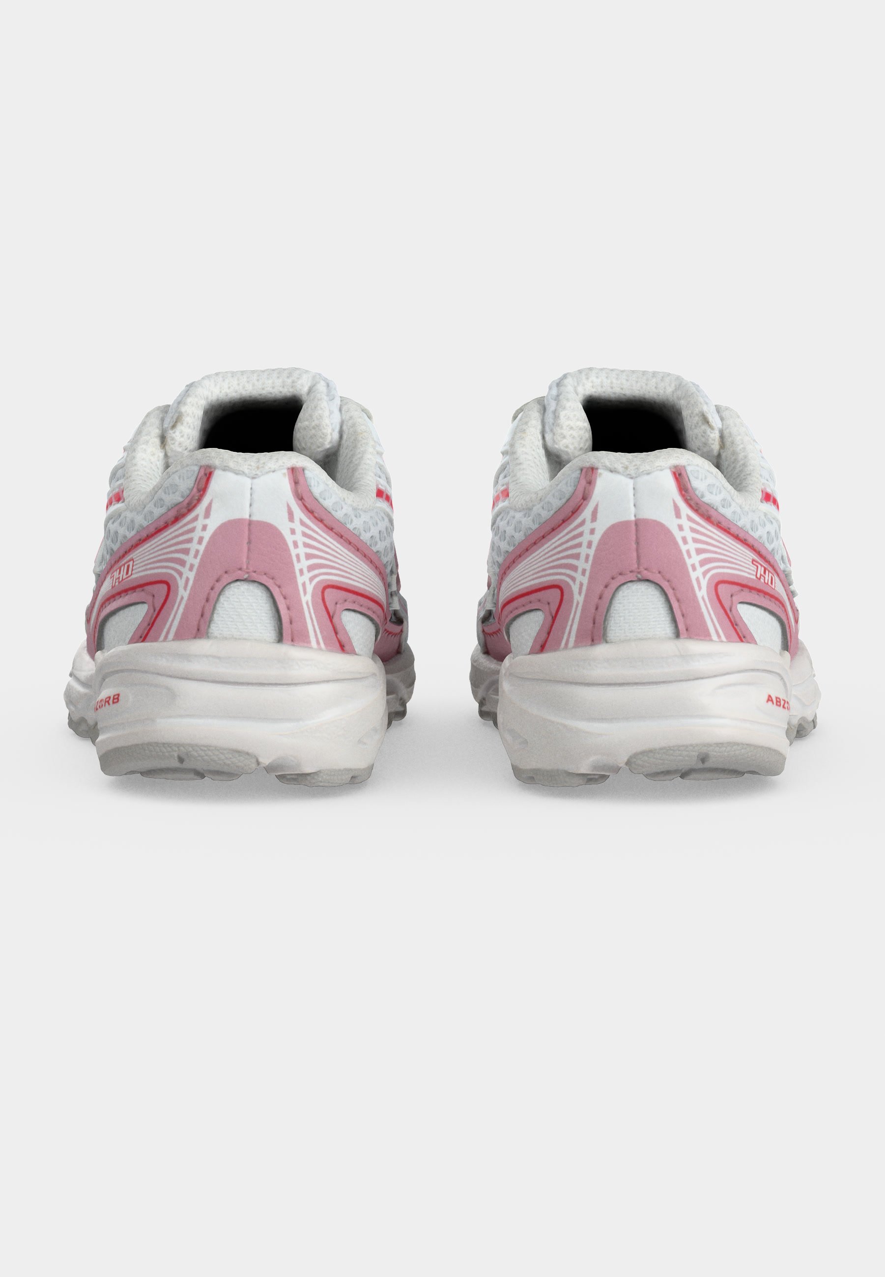 Par de zapatillas de deporte blancas y rosas vistas desde atrás sobre un fondo claro y liso.