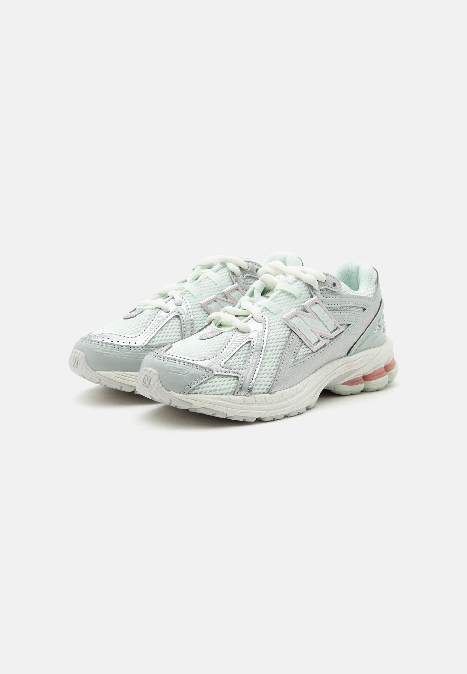 Par de zapatillas deportivas blancas y grises de New Balance con tejido de malla y suelas acolchadas, exhibidas sobre un fondo claro y liso.