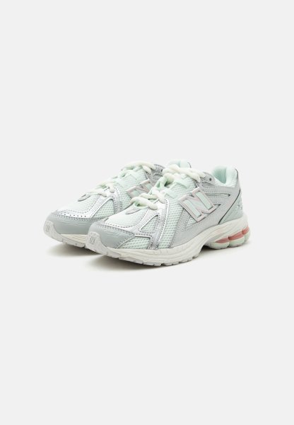 Par de zapatillas deportivas blancas y grises de New Balance con tejido de malla y suelas acolchadas, exhibidas sobre un fondo claro y liso.