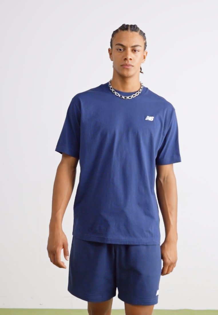 Camiseta de algodón de color azul marino con mangas cortas, que presenta un pequeño logo blanco en el lado izquierdo del pecho, combinada con pantalones cortos a juego en color azul marino.