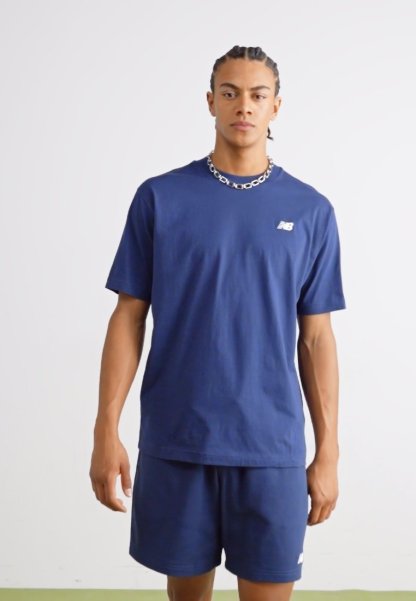 Camiseta de algodón de color azul marino con mangas cortas, que presenta un pequeño logo blanco en el lado izquierdo del pecho, combinada con pantalones cortos a juego en color azul marino.