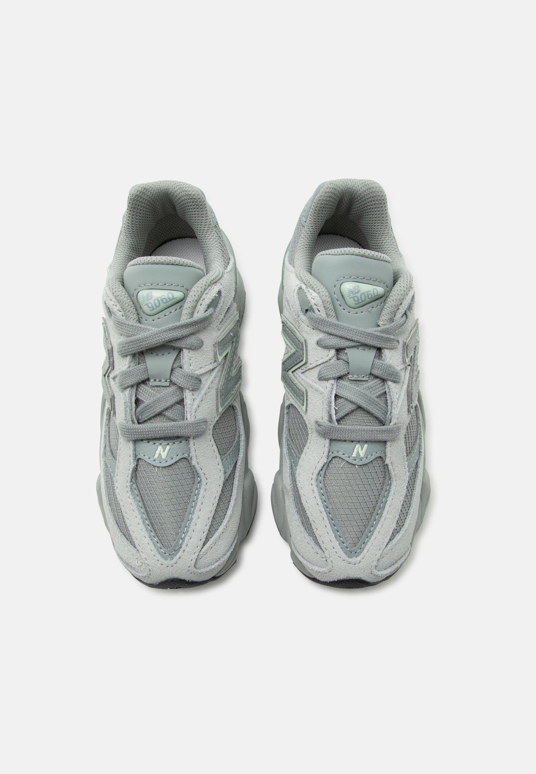 Par de zapatillas New Balance 9060 de color gris claro con detalles de malla y ante, atadas y vistas desde arriba sobre fondo blanco.