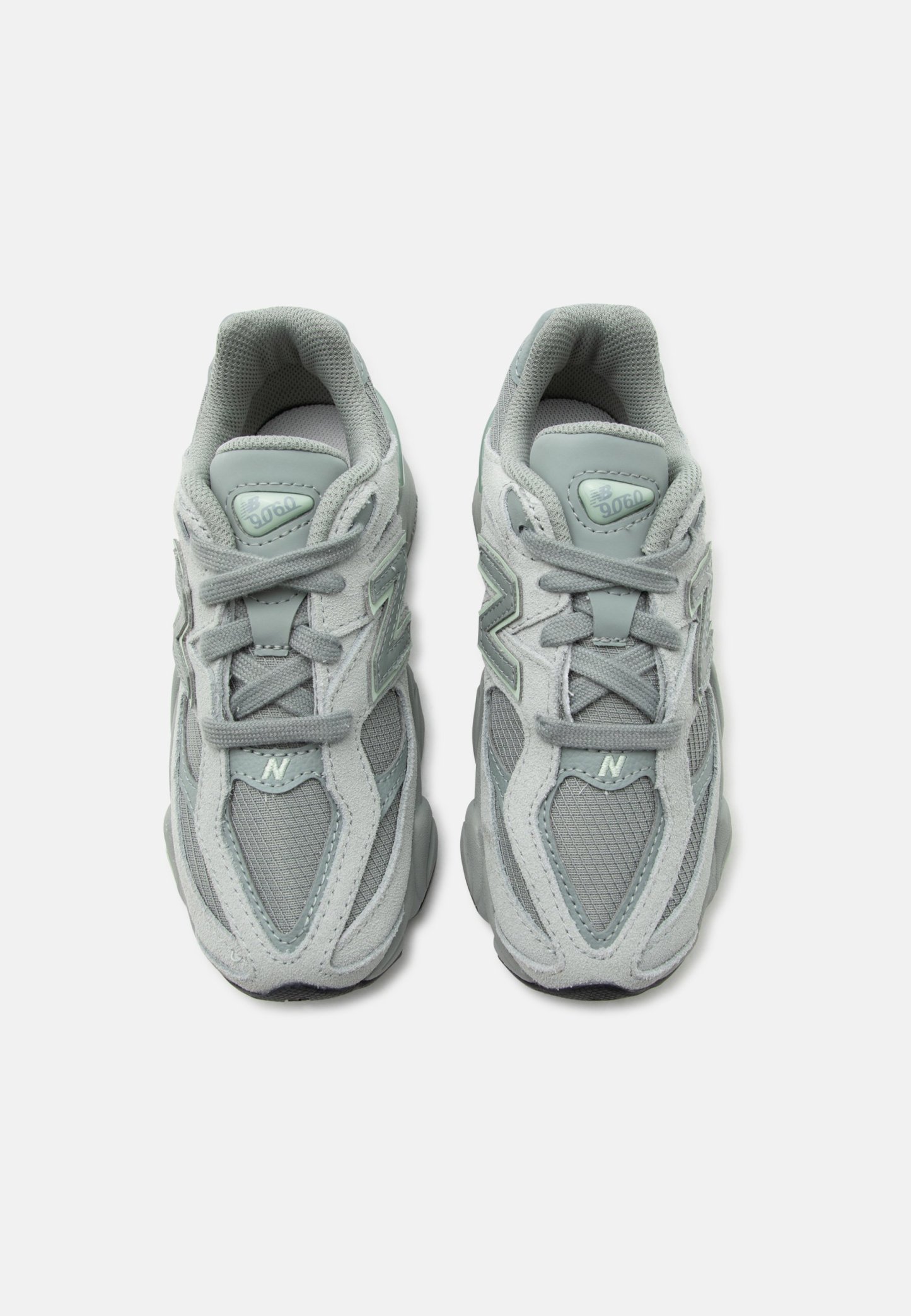 Par de zapatillas New Balance 9060 de color gris claro con detalles de malla y ante, atadas y vistas desde arriba sobre fondo blanco.