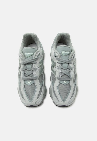 Par de zapatillas New Balance 9060 de color gris claro con detalles de malla y ante, atadas y vistas desde arriba sobre fondo blanco.