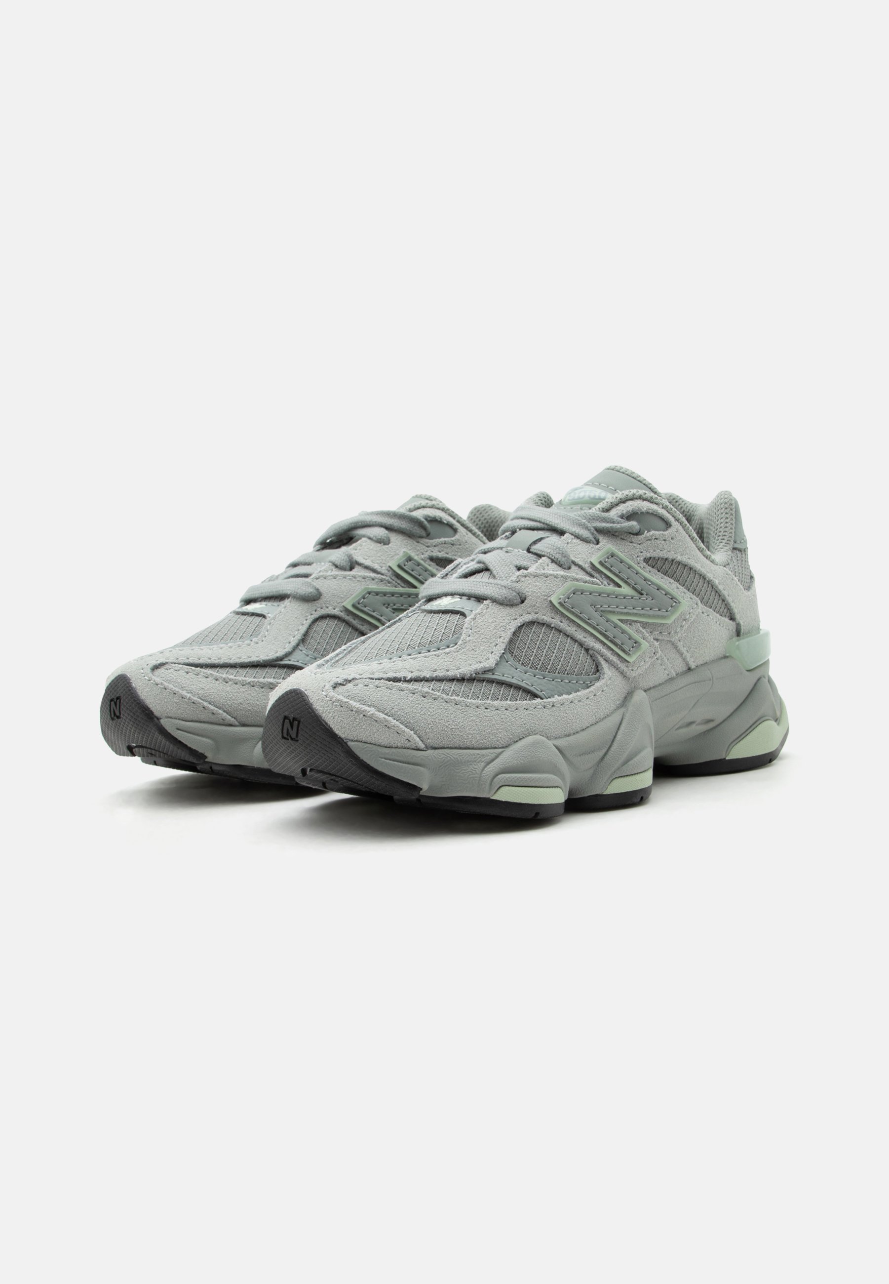 Par de zapatillas deportivas New Balance en gris claro y verde menta con parte superior de malla y ante, suelas gruesas y cordones sobre fondo blanco.