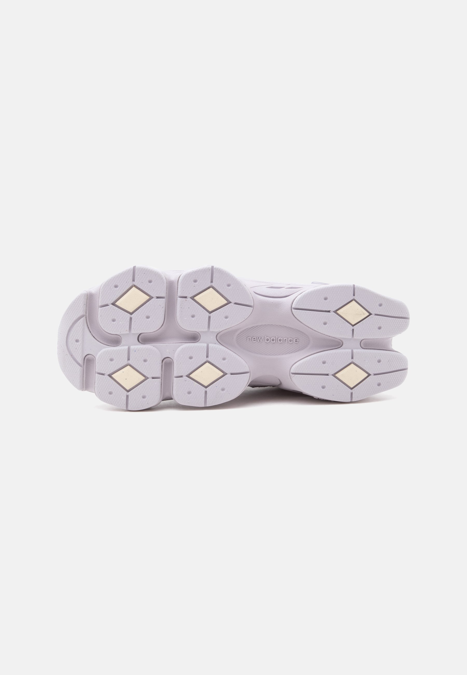 Suela blanca de zapatilla New Balance con patrones de dibujo en forma de diamante y logo grabado en el centro sobre un fondo liso.