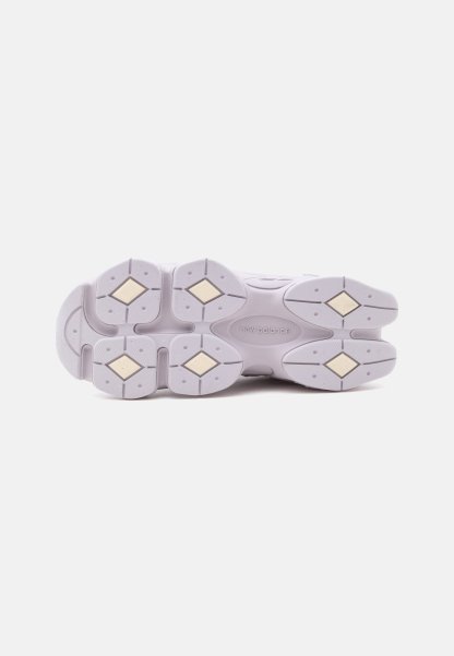 Suela blanca de zapatilla New Balance con patrones de dibujo en forma de diamante y logo grabado en el centro sobre un fondo liso.