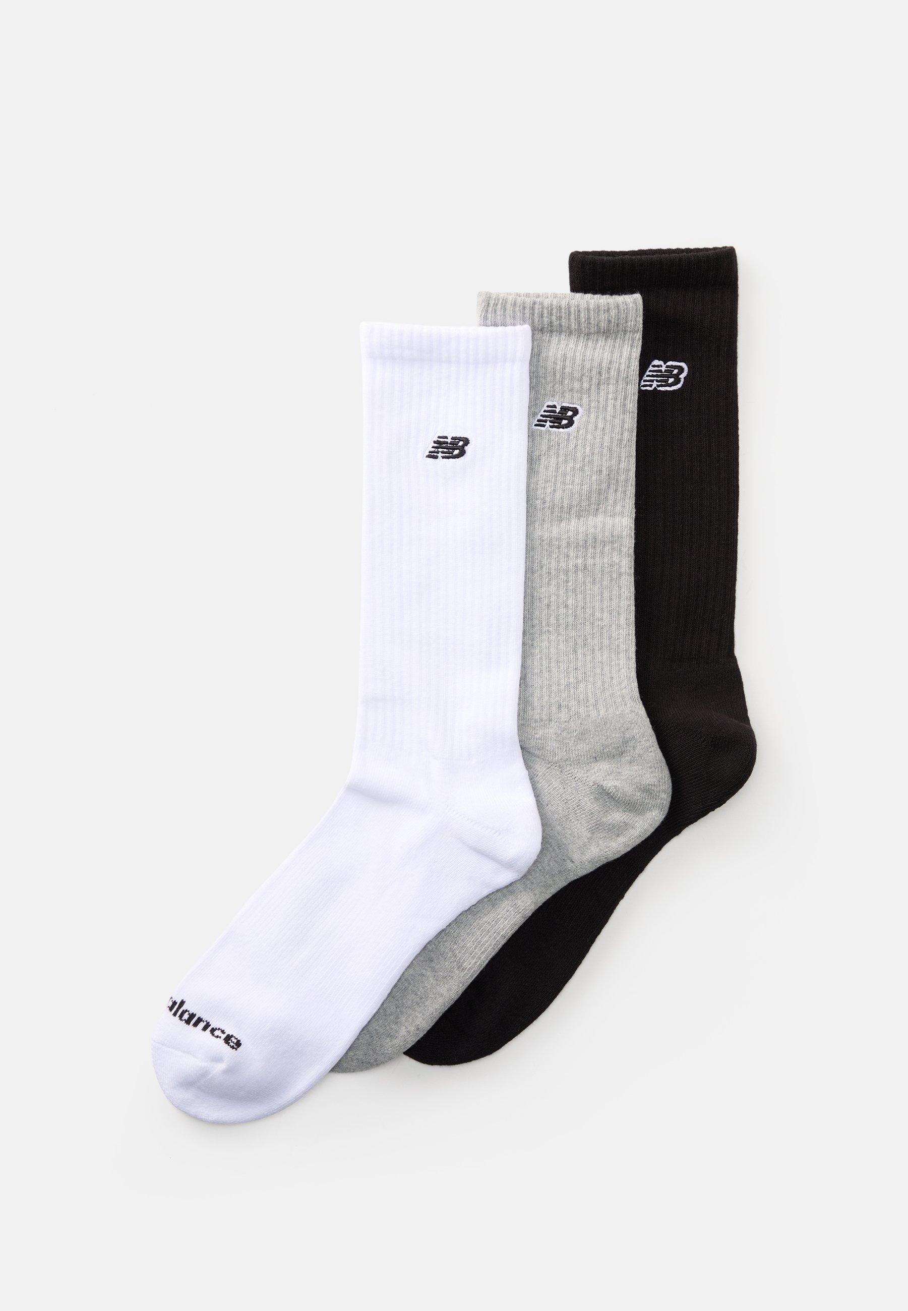 Tres pares de calcetines New Balance en blanco, gris y negro. Cada uno presenta un textura acanalada y el logo en la parte superior.