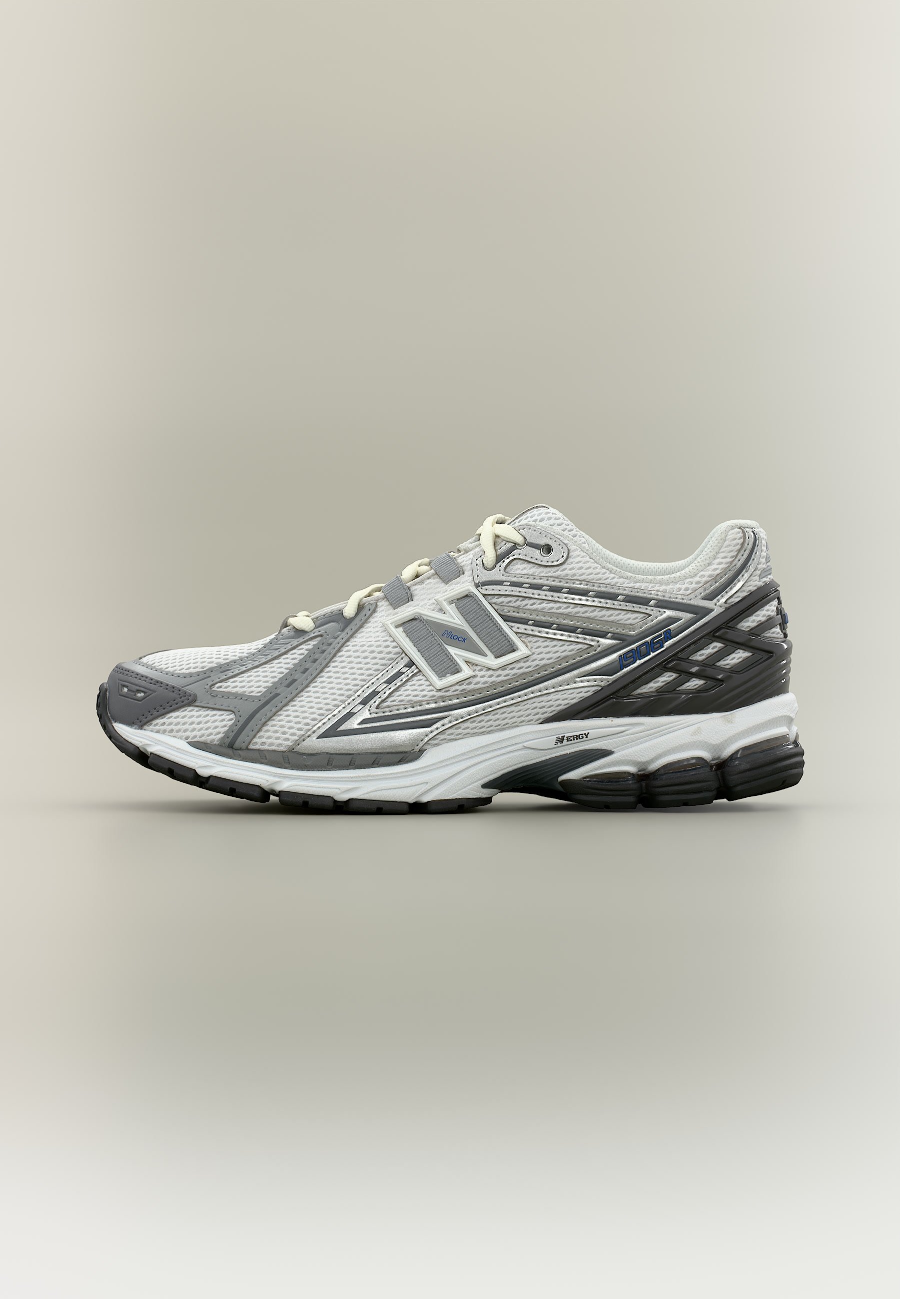 Zapatilla de running New Balance blanca y gris con parte superior de malla, logo de la marca, suela acolchada y suela exterior negra, mostrada sobre fondo neutro.