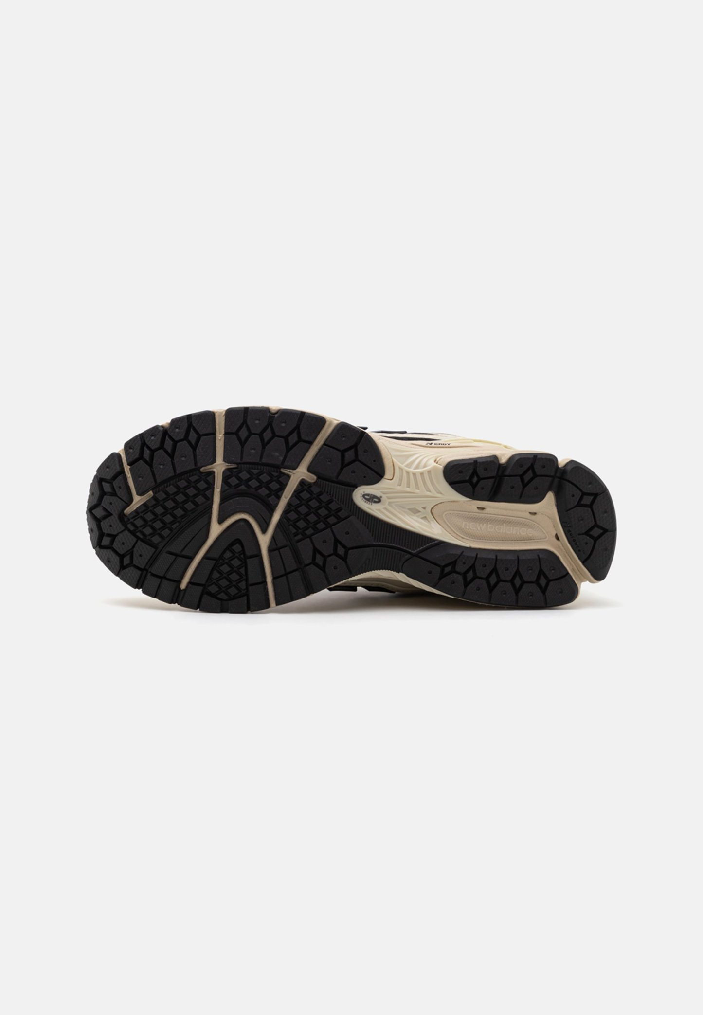 Suela de zapato deportivo New Balance beige y negro con patrón de agarre texturizado y logo visible en los laterales y el talón.