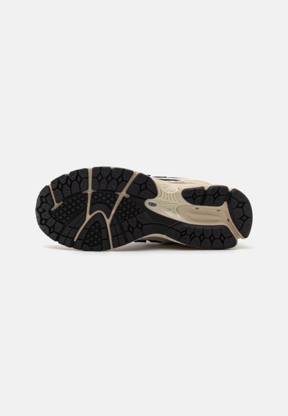 Suela de zapato deportivo New Balance beige y negro con patrón de agarre texturizado y logo visible en los laterales y el talón.