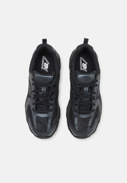 Zapatillas atléticas negras con material de malla y sintético, que presentan un diseño con cordones, cuello acolchado y acentos texturizados.