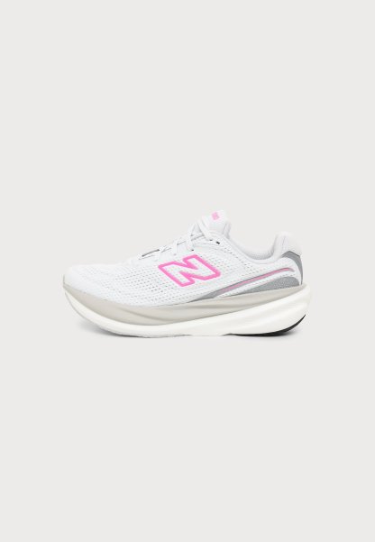 Zapatilla de correr blanca y gris con logo rosa "N" en la parte superior de malla y suela acolchada gruesa, mostrada de lado sobre fondo blanco.