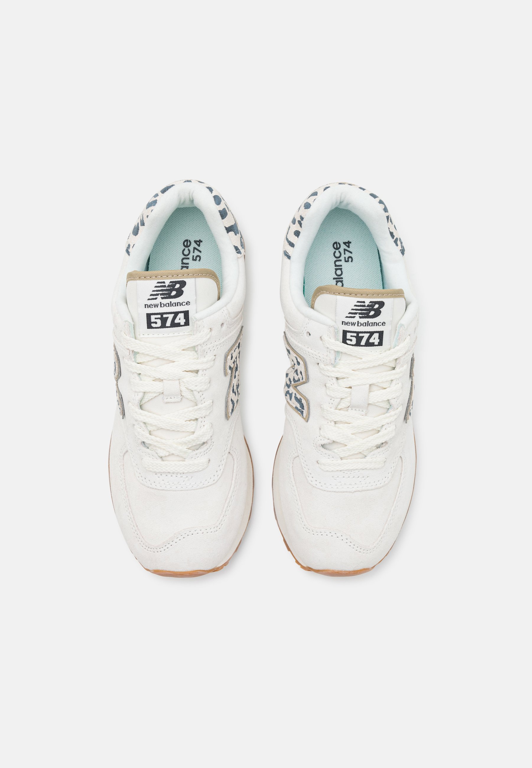 Par de zapatillas blancas New Balance 574 con detalles de estampado de leopardo en los lados y alrededor del cuello, vistas desde arriba.