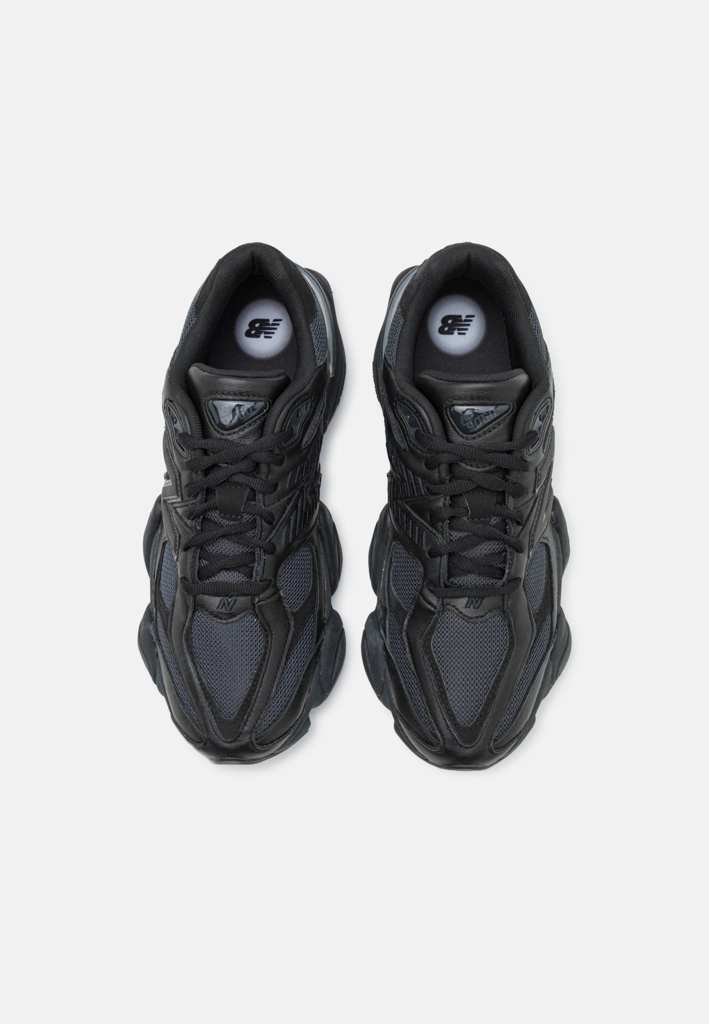 Zapatillas deportivas negras con parte superior de malla y sintético, que cuentan con una suela gruesa, acentos texturizados y un logotipo prominente en la lengüeta.