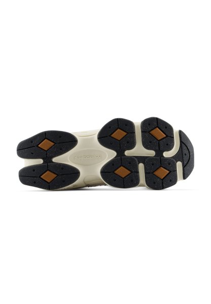Suela de un zapato New Balance que muestra almohadillas de tracción de goma negras y marrones sobre una base blanca con el nombre de la marca en relieve en el centro.