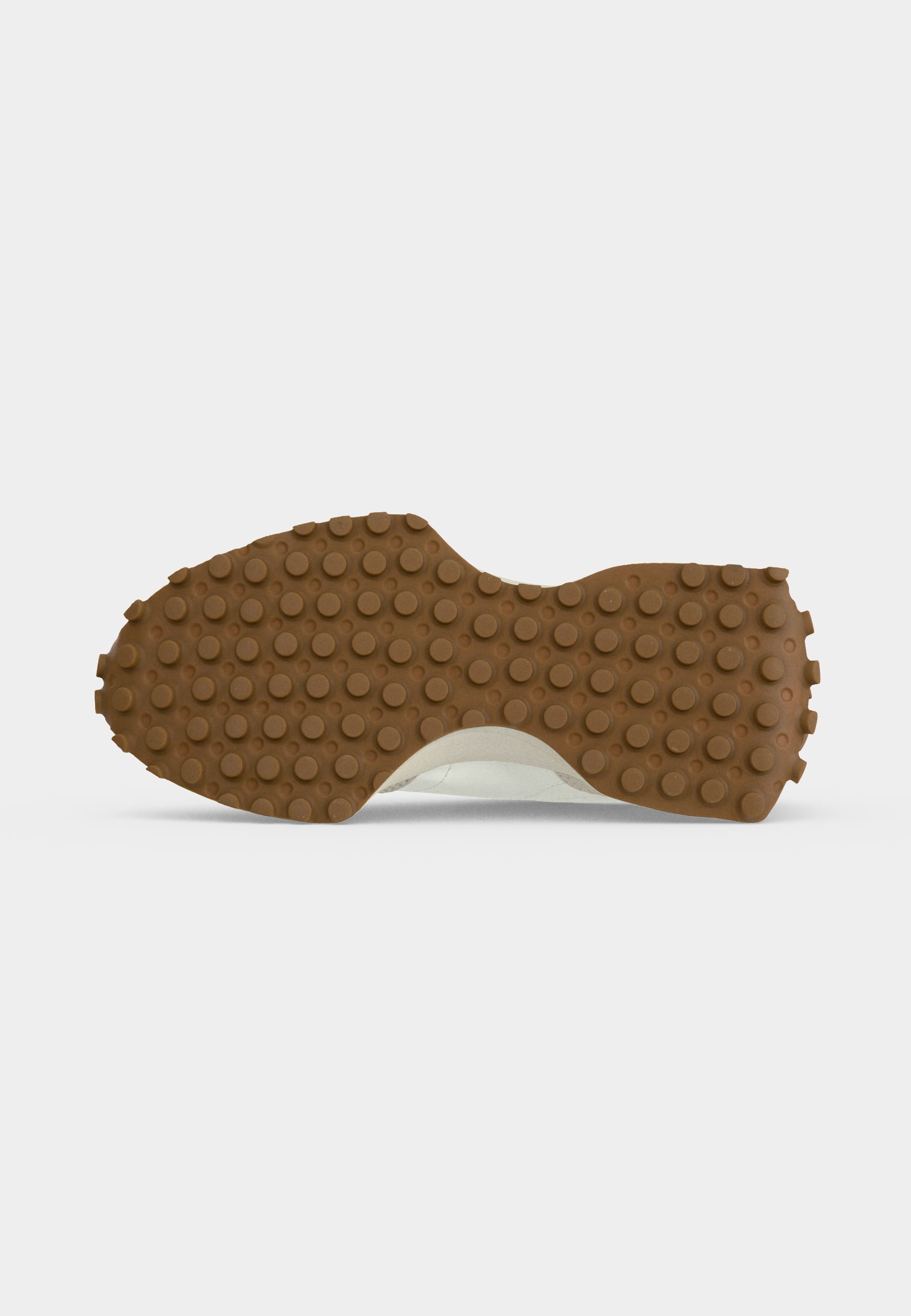 Suela de zapato con tracción de goma marrón con tachuelas circulares uniformemente espaciadas para agarre, presentada sobre un fondo blanco liso.
