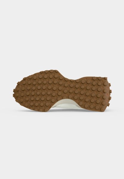 Suela de zapato con tracción de goma marrón con tachuelas circulares uniformemente espaciadas para agarre, presentada sobre un fondo blanco liso.