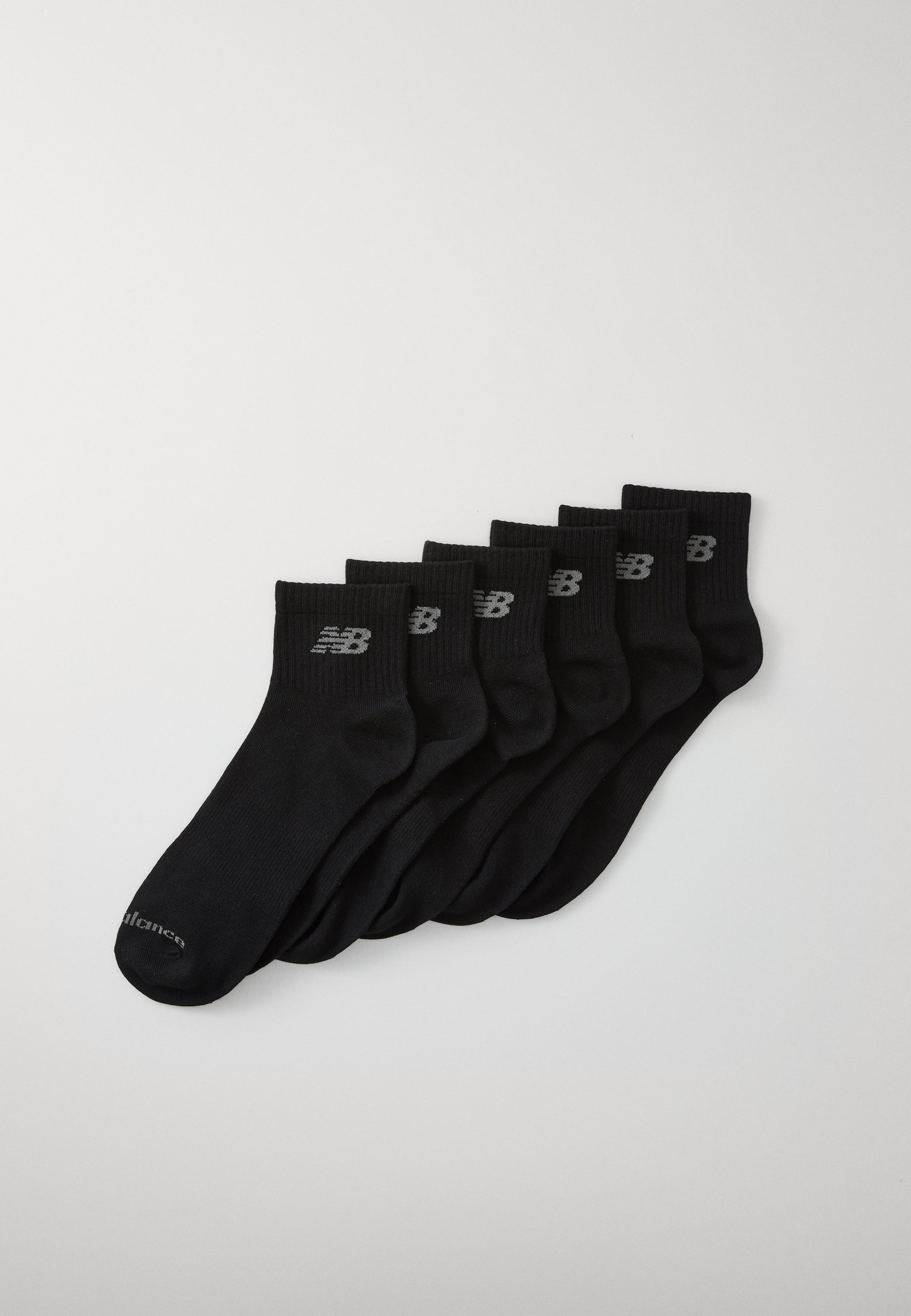 Calcetines de algodón negros organizados en una pila, con un diseño acanalado y el logotipo visible de New Balance en gris en la parte superior.
