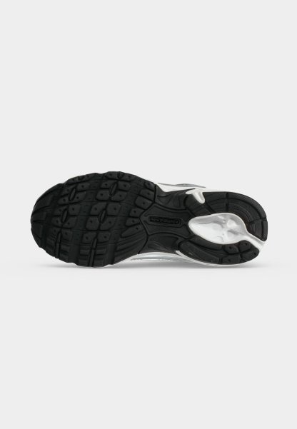 Suela de zapato deportivo en blanco y negro con tacos texturizados y logo de New Balance en el centro, vista desde abajo sobre fondo blanco.