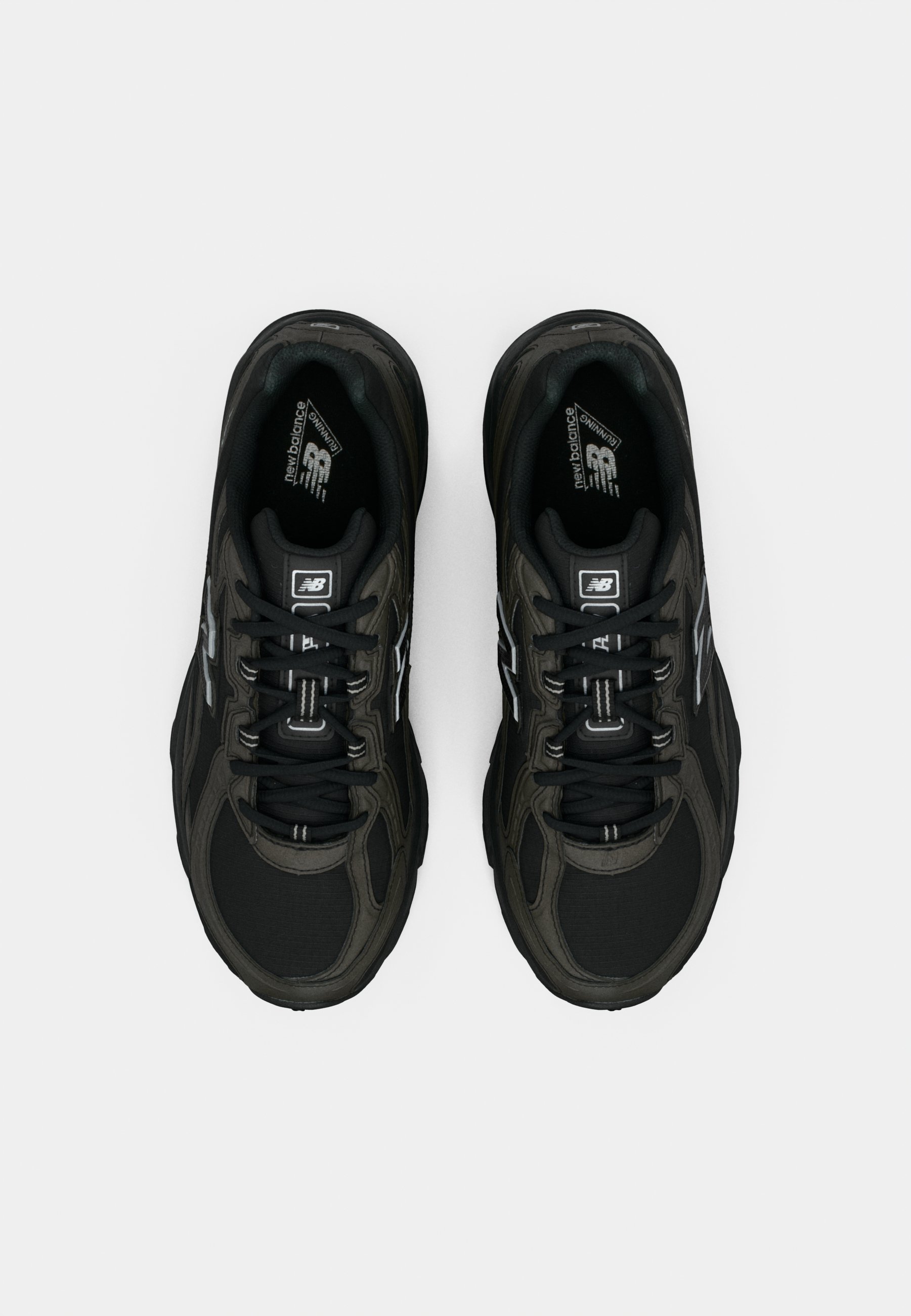 Zapatillas deportivas negras con parte superior de malla y sintético, que presentan acentos reflectantes, suelas resistentes y cordones tradicionales. Sin logotipos prominentes visibles.