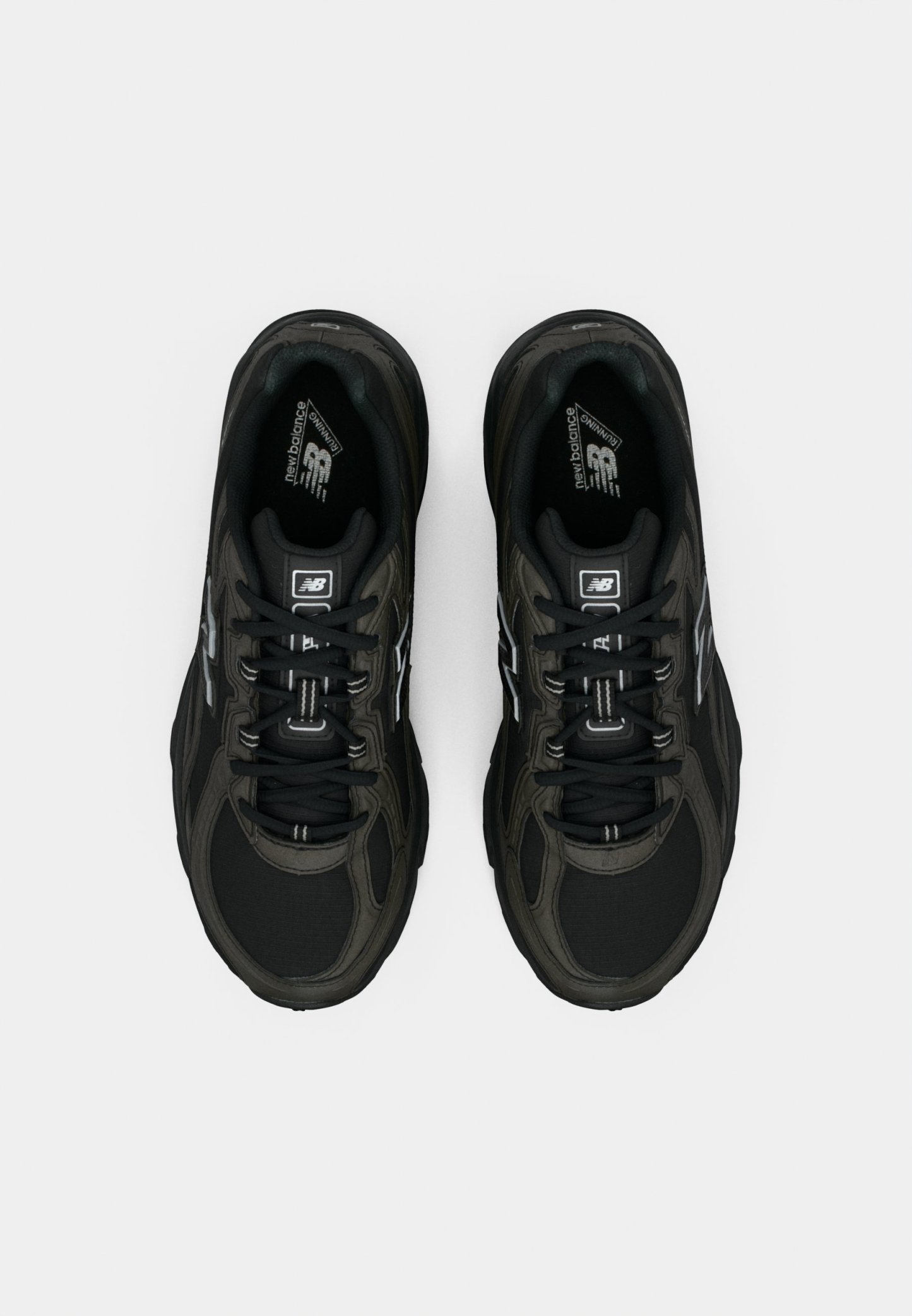 Zapatillas deportivas negras con parte superior de malla y sintético, que presentan acentos reflectantes, suelas resistentes y cordones tradicionales. Sin logotipos prominentes visibles.