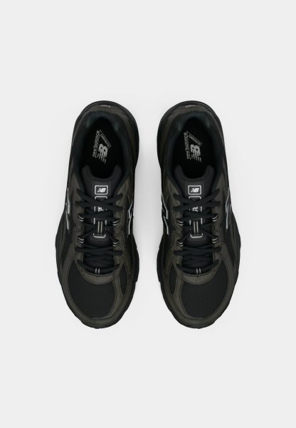 Zapatillas deportivas negras con parte superior de malla y sintético, que presentan acentos reflectantes, suelas resistentes y cordones tradicionales. Sin logotipos prominentes visibles.